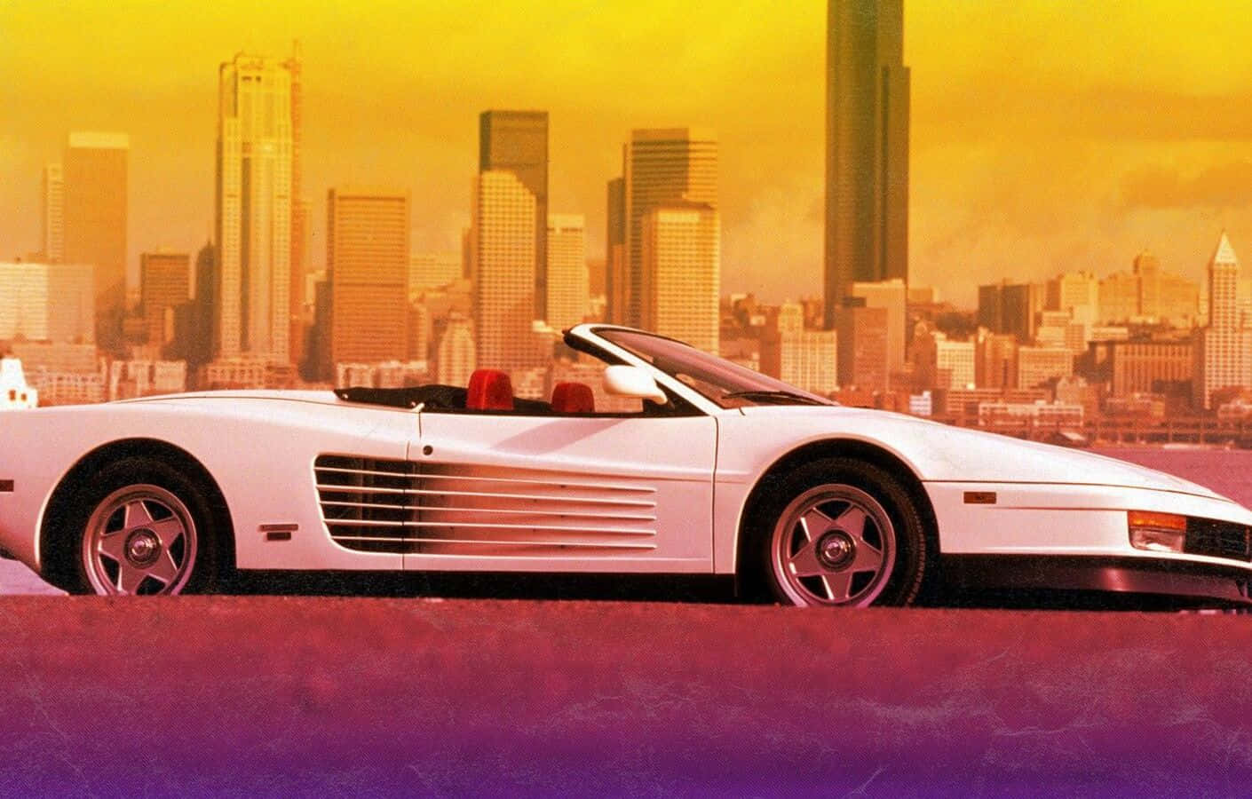 Ferrari Testarossa 桌布 壁紙 — 一輛白色敞篷跑車配紅色座椅，停放在紫色表面上，背景是日落時分金黃色的城市天際線。