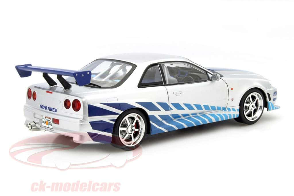 Paul Walker Skyline 桌布 壁紙 — 一輛白色日產Skyline GT-R模型車，帶有藍色賽車條紋和大型尾翼，置於潔白背景上。