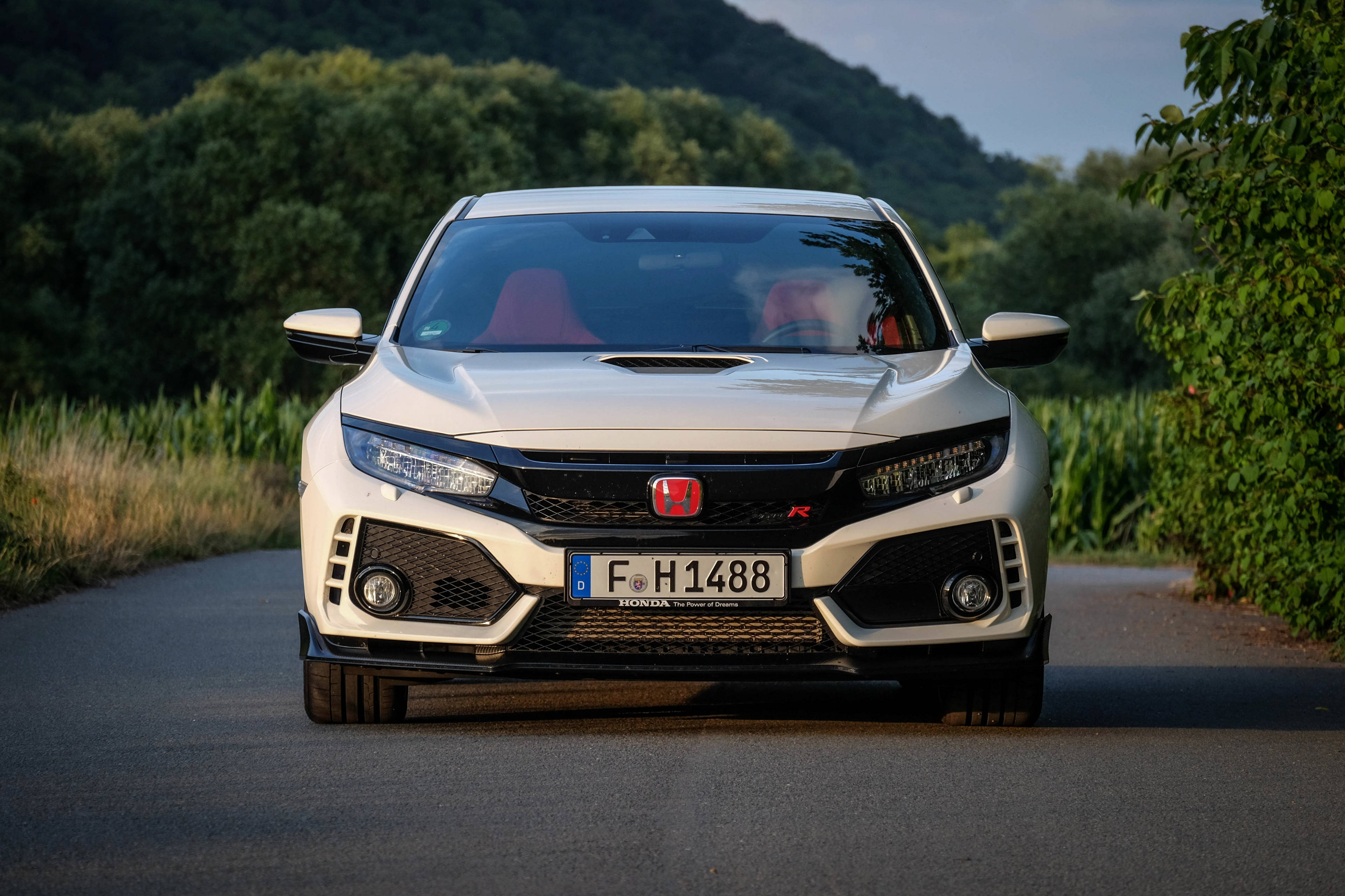 高清 桌布 壁紙 — 一輛白色本田Civic Type R在蜿蜒的鄉村道路上向前行駛，兩旁是茂密的綠樹和山丘，沐浴在柔和的晚光中。