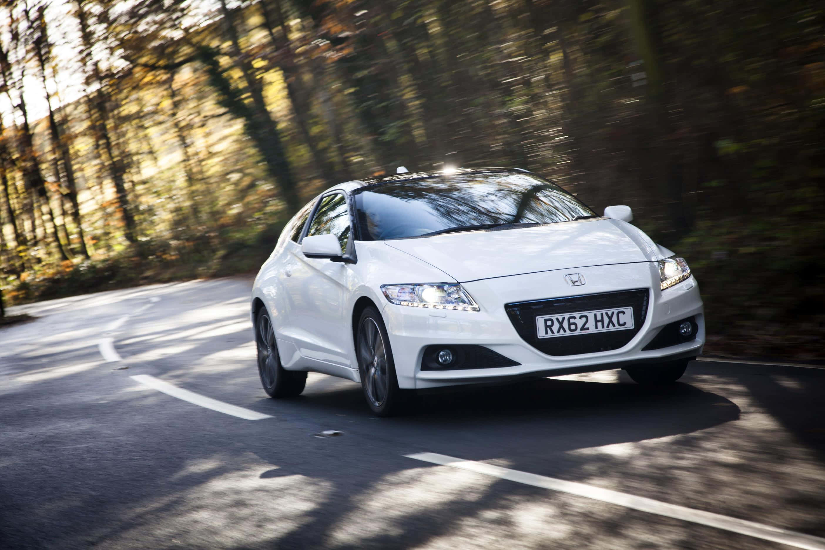 Honda Cr-z 桌布 壁紙 — 一輛白色本田CR-Z在蜿蜒的林間道路上疾馳，秋天的樹木在運動中模糊掠過。