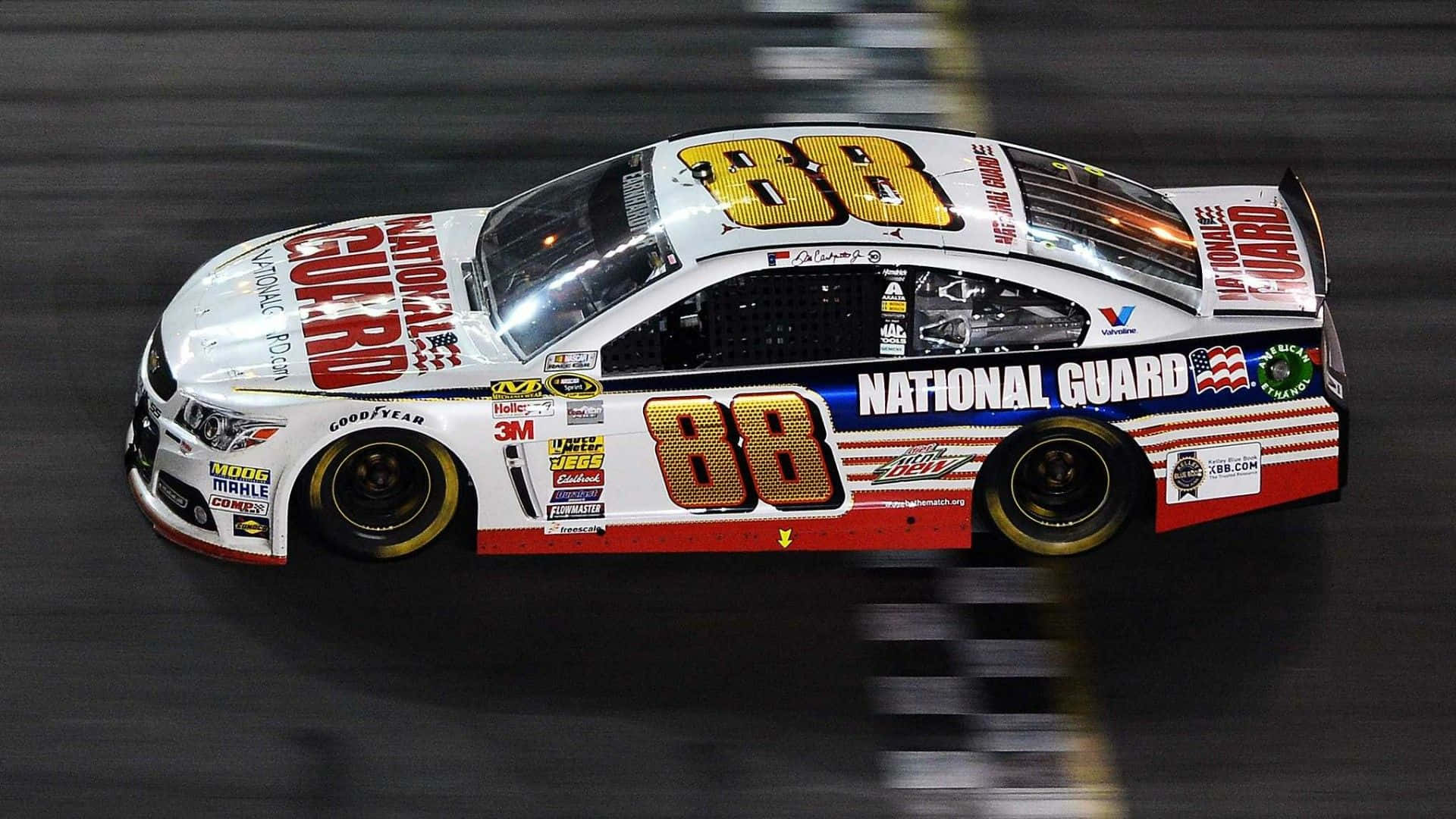nascar 桌布 壁紙 — 一輛白色的National Guard賽車，編號88，在明亮的體育場燈光下，於夜間模糊的賽道上奔馳。