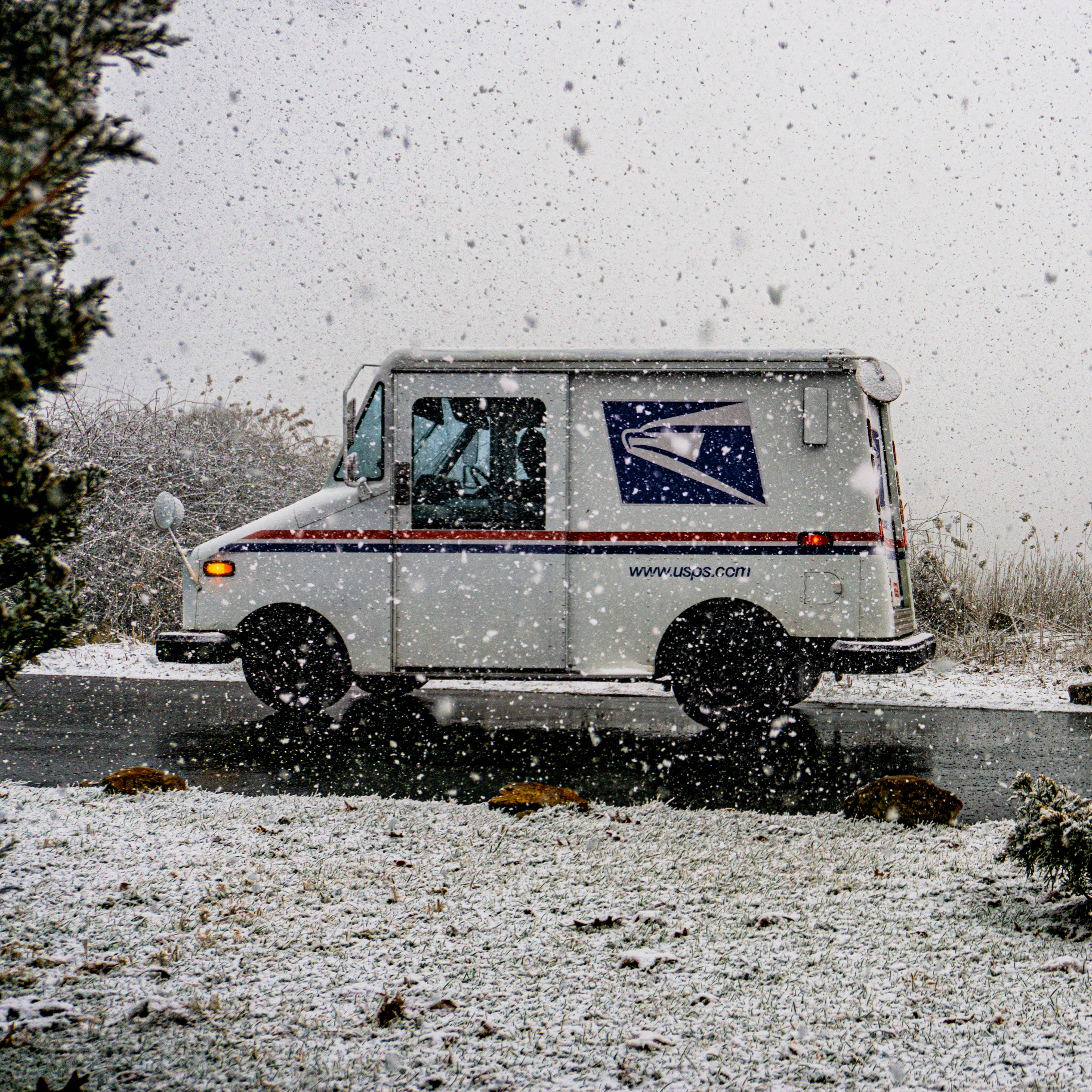 雪 桌布 壁紙 — 一輛白色的USPS郵政車在雪景中行駛，雪花飄落，草地結霜。