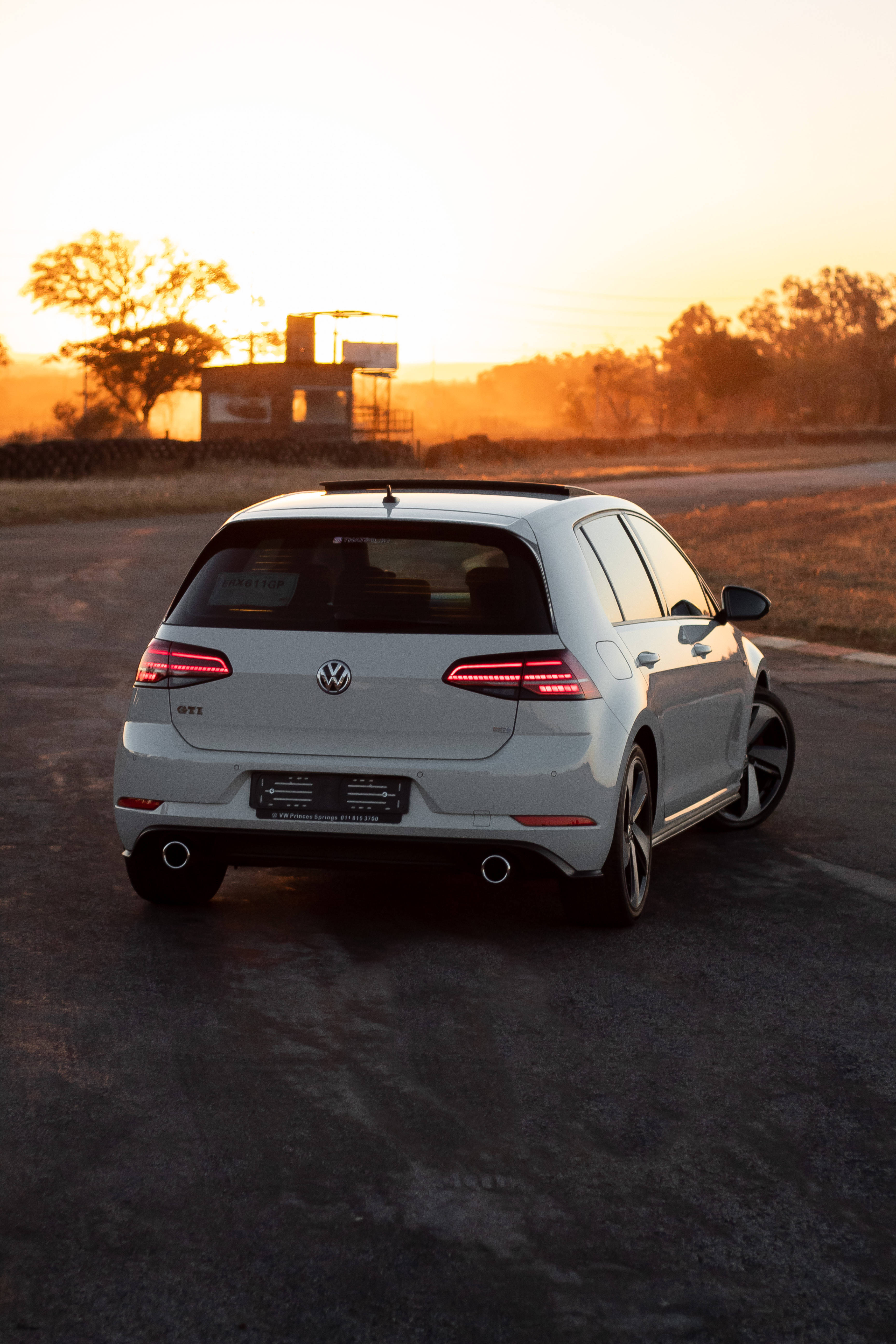 Gti 桌布 壁紙 — 一輛白色福斯Golf GTI在日落時停泊在瀝青路上，溫暖的金色陽光投下長長的影子。
