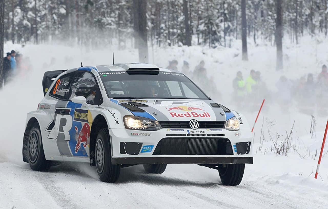 Ice Racing 桌布 壁紙 — 一輛白色福斯拉力賽車帶有紅牛塗裝，在雪地森林賽道上疾馳，揚起雪霧。