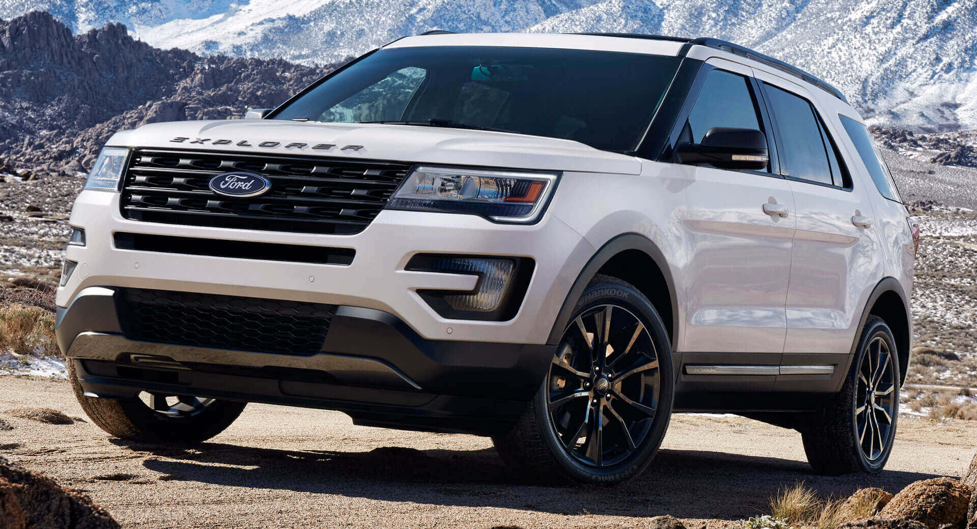 Ford Explorer 桌布 壁紙 — 一輛白色福特Explorer SUV停放在岩石地形上，背景是白雪覆蓋的山脈，在明亮的日光下。