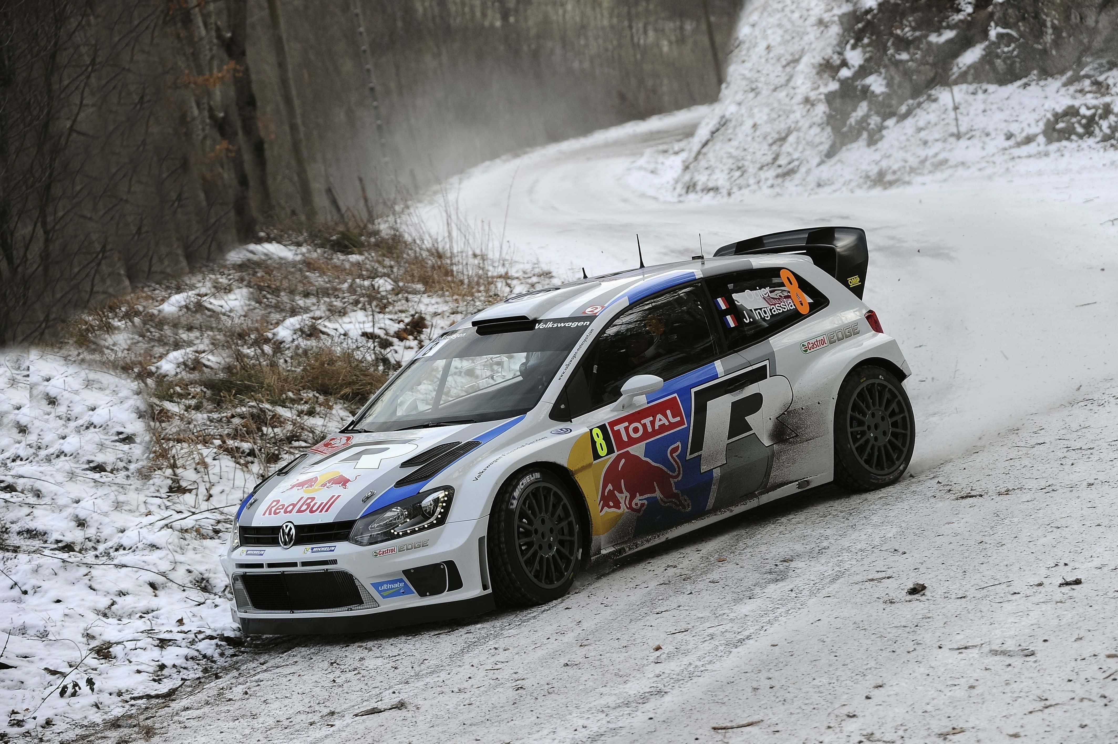 Ice Racing 桌布 壁紙 — 一輛白色紅牛拉力賽車在積雪的森林彎路上奔馳，激起雪霧。