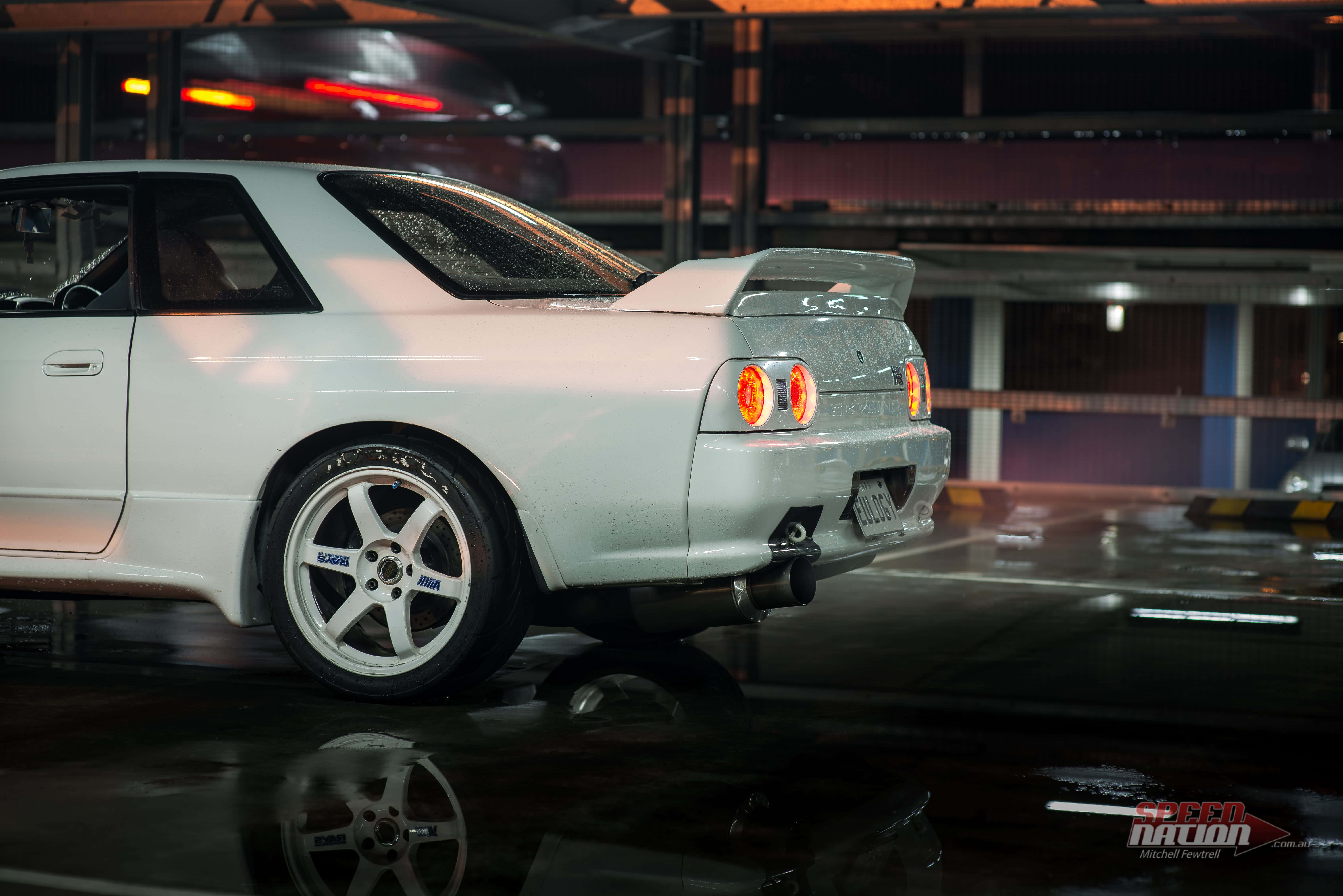 Aesthetic Car 桌布 壁紙 — 一輛白色經典跑車，帶有發光的尾燈，停在夜間潮濕的地下車庫中。
