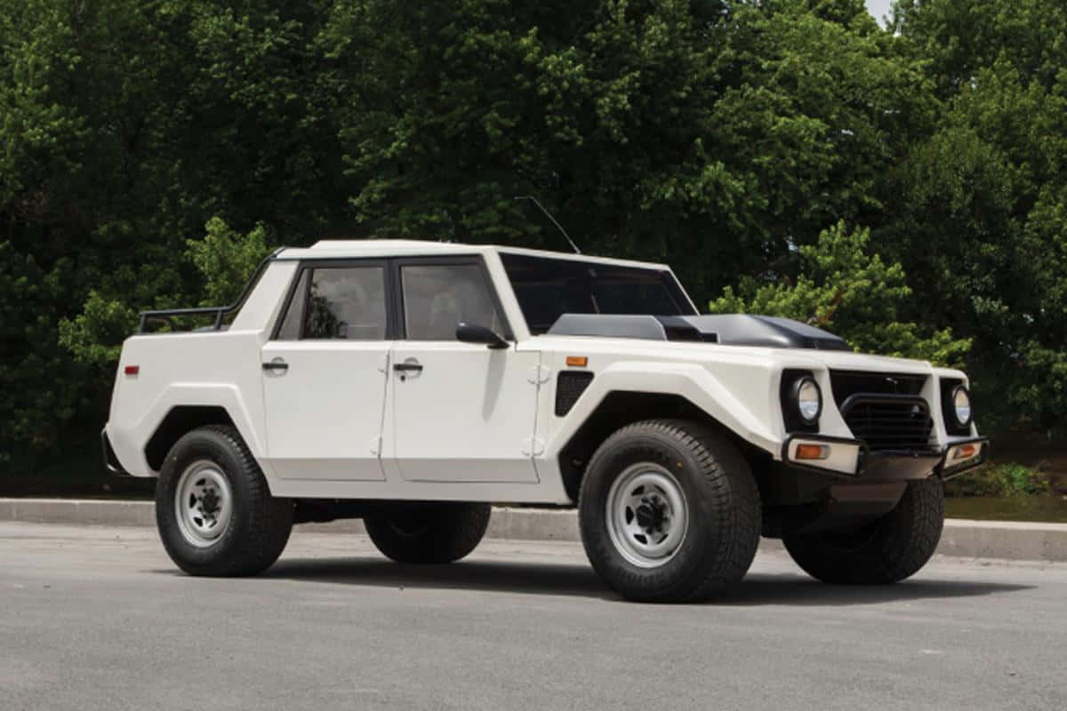 Lamborghini Lm002 桌布 壁紙 — 一輛白色藍寶堅尼LM002裝甲SUV停在柏油路上，背景有茂密的綠樹。