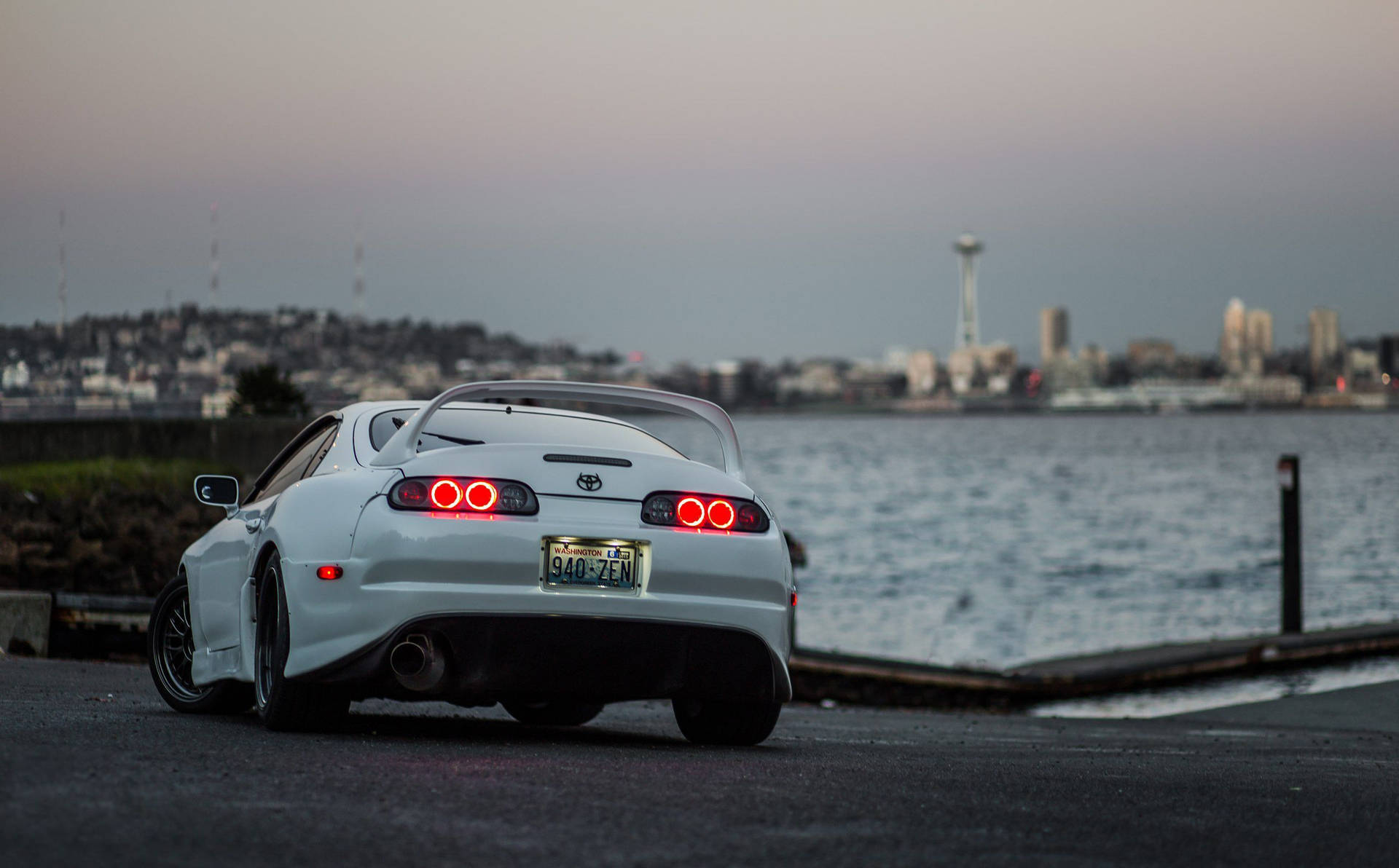 白色豐田Supra停在海濱，背景是黃昏時分的西雅圖天際線。 — Toyota Supra Mk4 壁紙