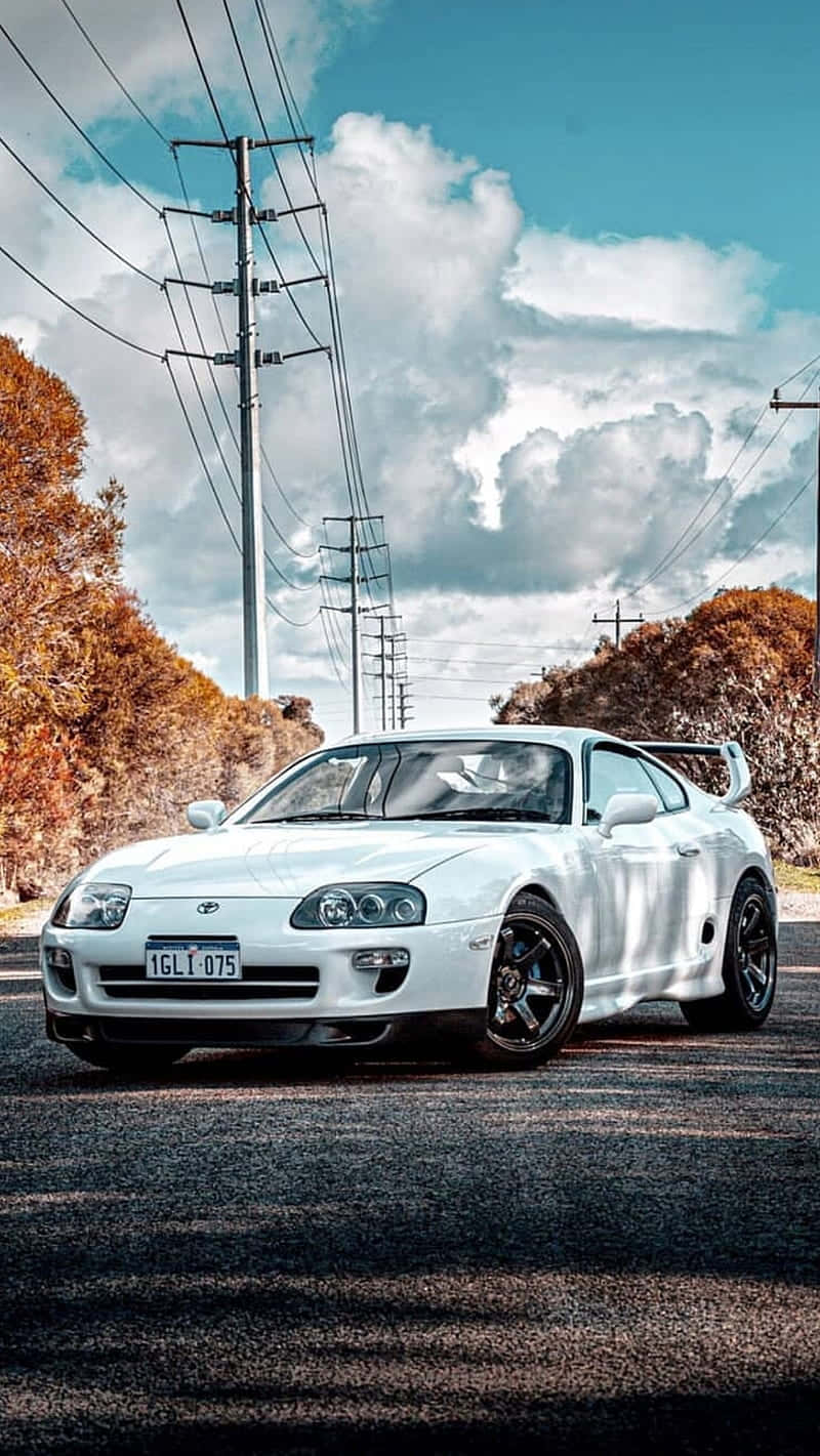白色豐田Supra停泊在一條有秋樹和電線的路上，天空多雲。 — Toyota Supra Mk4 壁紙