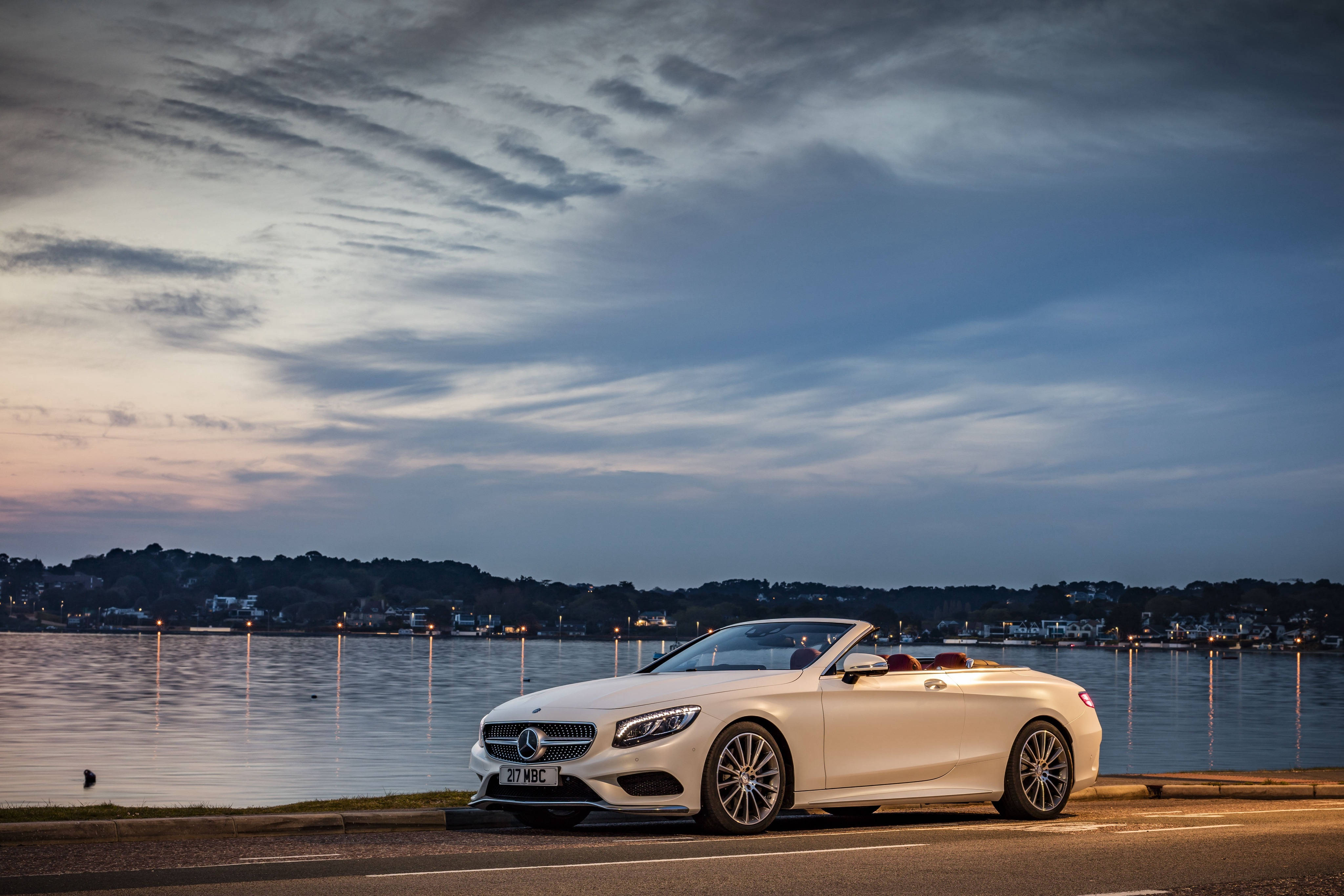 benz 4K 桌布 壁紙 — 一輛白色賓士敞篷車停泊在黃昏時分寧靜的水邊，天空的柔和倒影映照在水面上。