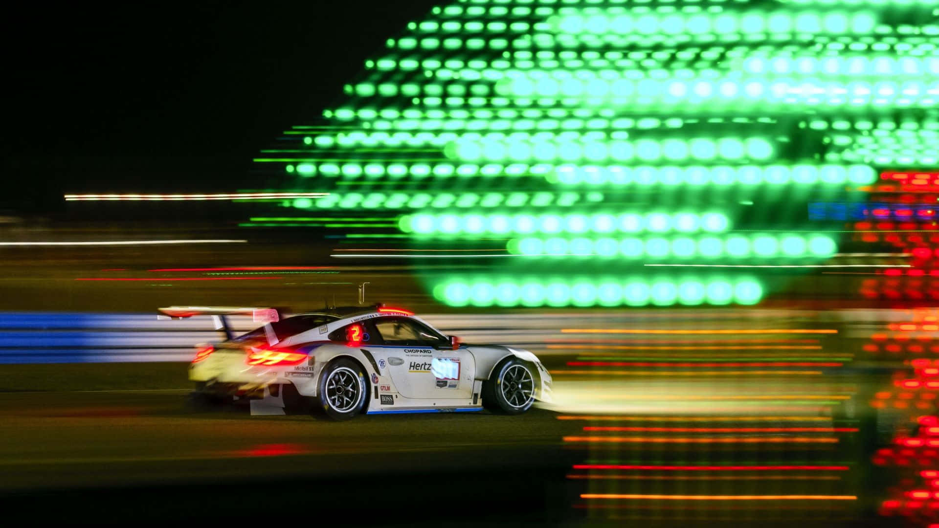Motion Blur 桌布 壁紙 — 一輛白色賽車在夜間模糊駛過，身後留下綠色、紅色和藍色的光條。