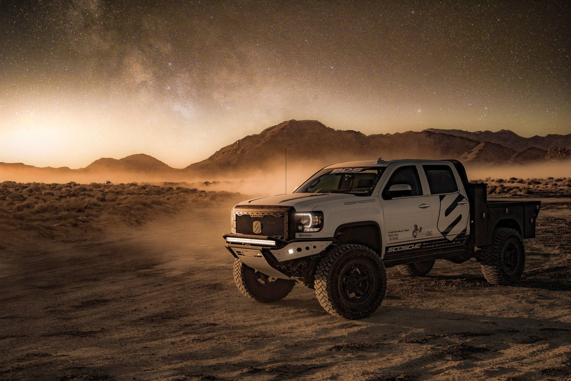 Trucks 桌布 壁紙 — 一輛白色越野車在星空下揚起塵土，背景是山脈。