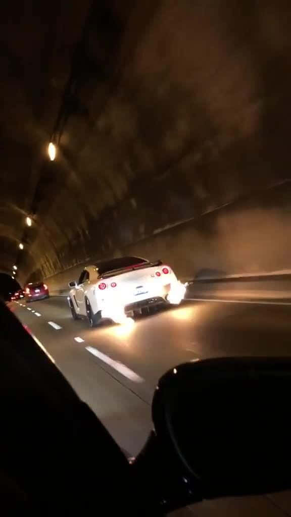 Nissan 桌布 壁紙 — 一輛白色跑車在燈光昏暗的隧道中疾馳，帶有發光的尾燈和動態模糊效果。