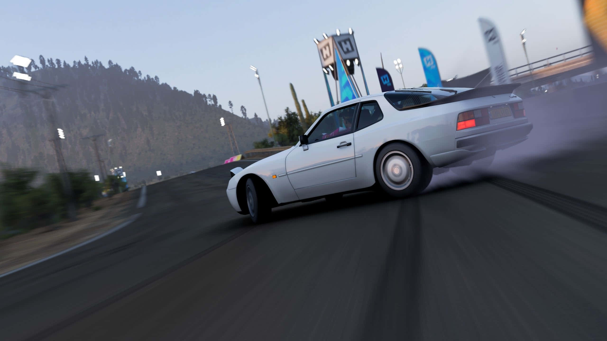 1440p Forza Motorsport 7 桌布 壁紙 — 一輛白色跑車在賽車場彎道漂移，揚起煙霧，背景是暮色中的山脈。