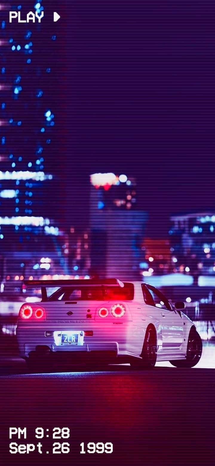 JDM 桌布 壁紙 — 一輛白色跑車帶著發光的紅色尾燈，在夜晚霓虹燈閃爍的城市景觀中飄移。