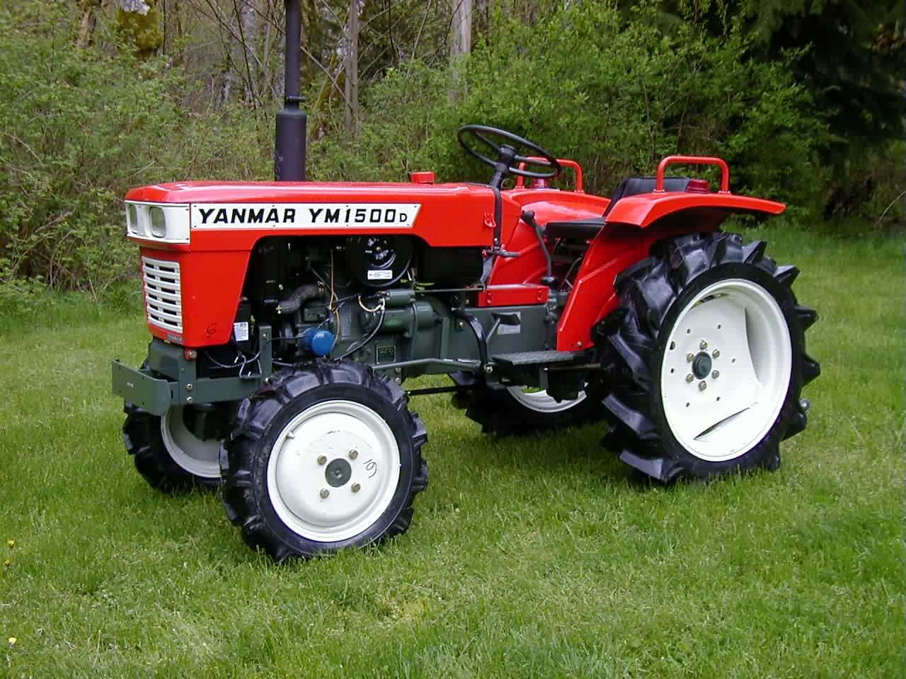 Tractor 桌布 壁紙 — 一輛白色車輪的鮮紅色Yanmar YM1500D拖拉機，站在茂密樹木環繞的翠綠草地上。