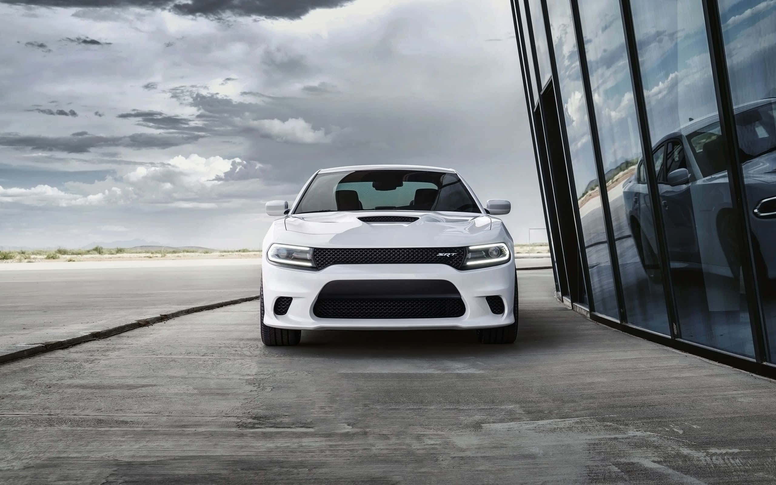 Dodge Charger 桌布 壁紙 — 一輛白色道奇挑戰者SRT Hellcat停放在玻璃建築旁邊的混凝土上，天空多雲。