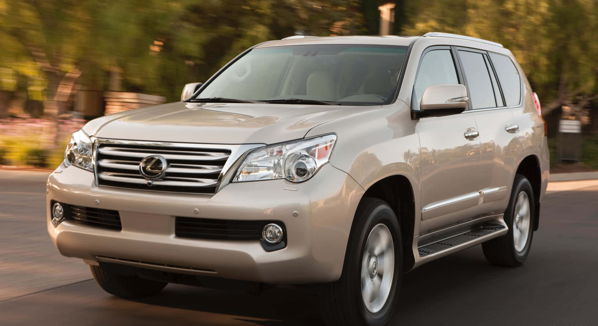 Lexus Gx 460 桌布 壁紙 — 一輛米色Lexus SUV在綠樹成蔭的道路上行駛，背景帶有動態模糊效果。