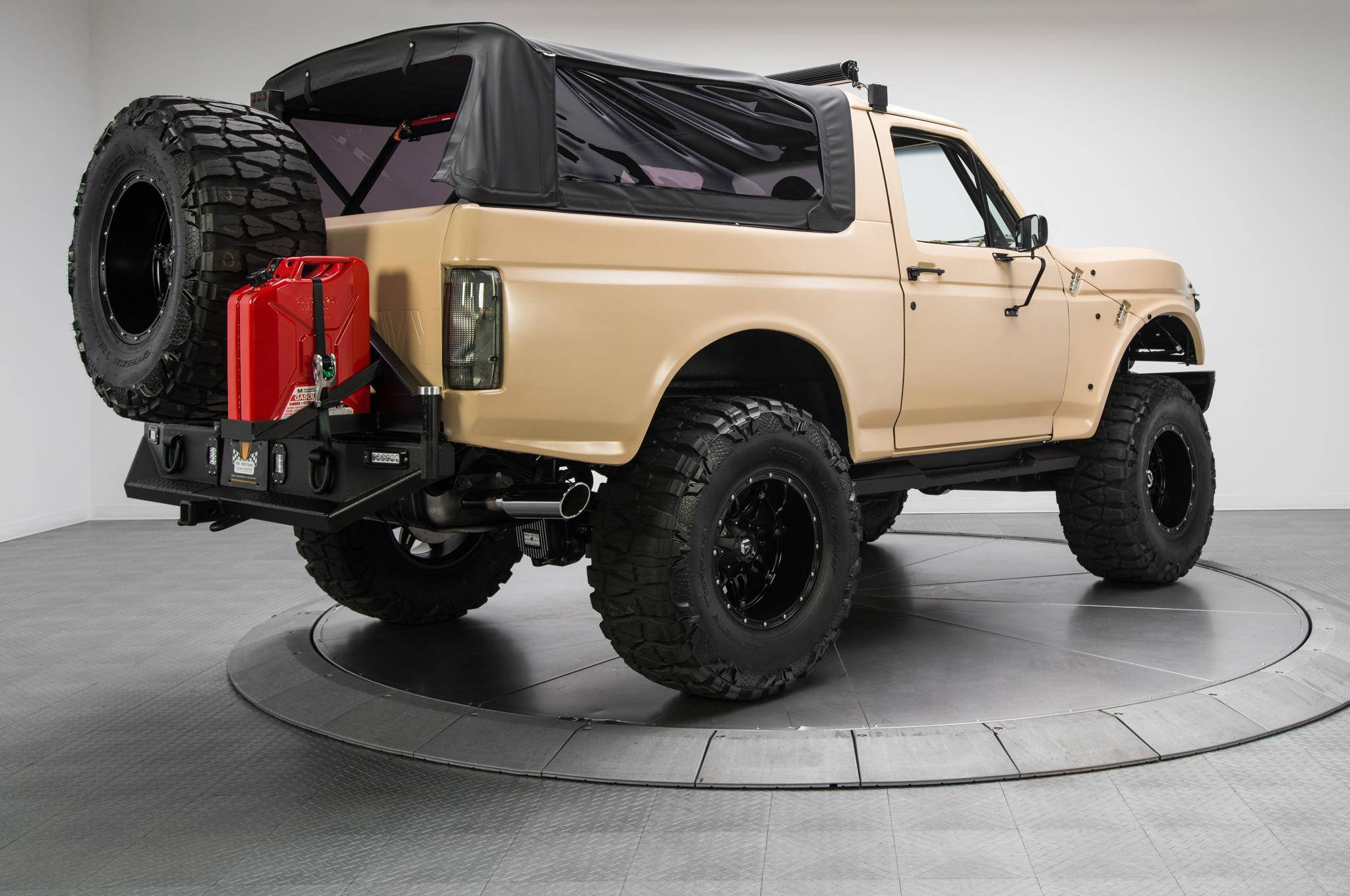 Ford Bronco 桌布 壁紙 — 一輛米色升高版福特Bronco，配備黑色輪胎和安裝在黑色後保險桿上的紅色燃油罐，停在工作室的旋轉平台上。
