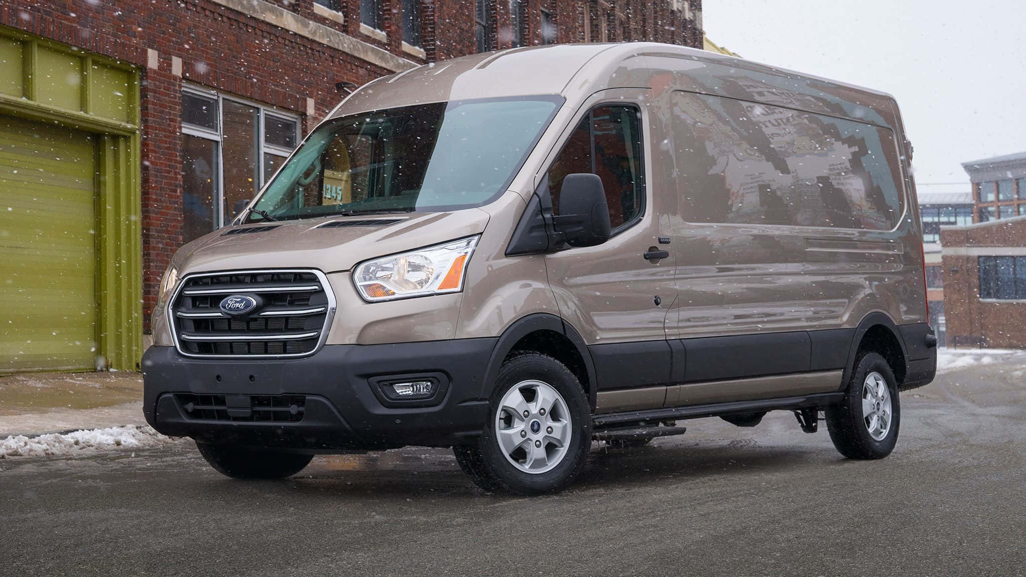Ford Transit 桌布 壁紙 — 一輛米色福特 Transit 客貨車停在磚造建築外，周圍輕輕飄落著雪花。