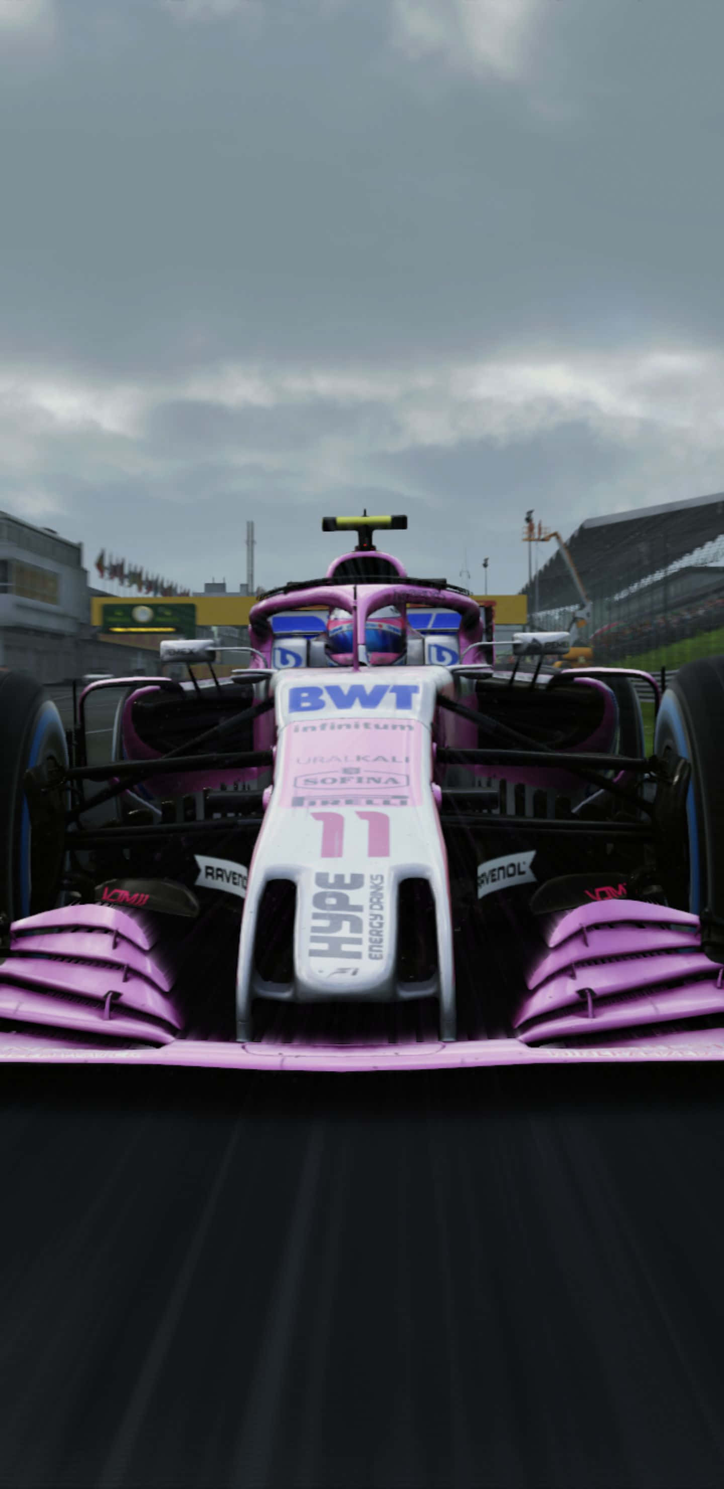 Formula 1 桌布 壁紙 — 一輛粉紅色和白色的 Formula 1 賽車，號碼 11，在陰天下的賽道上疾馳。