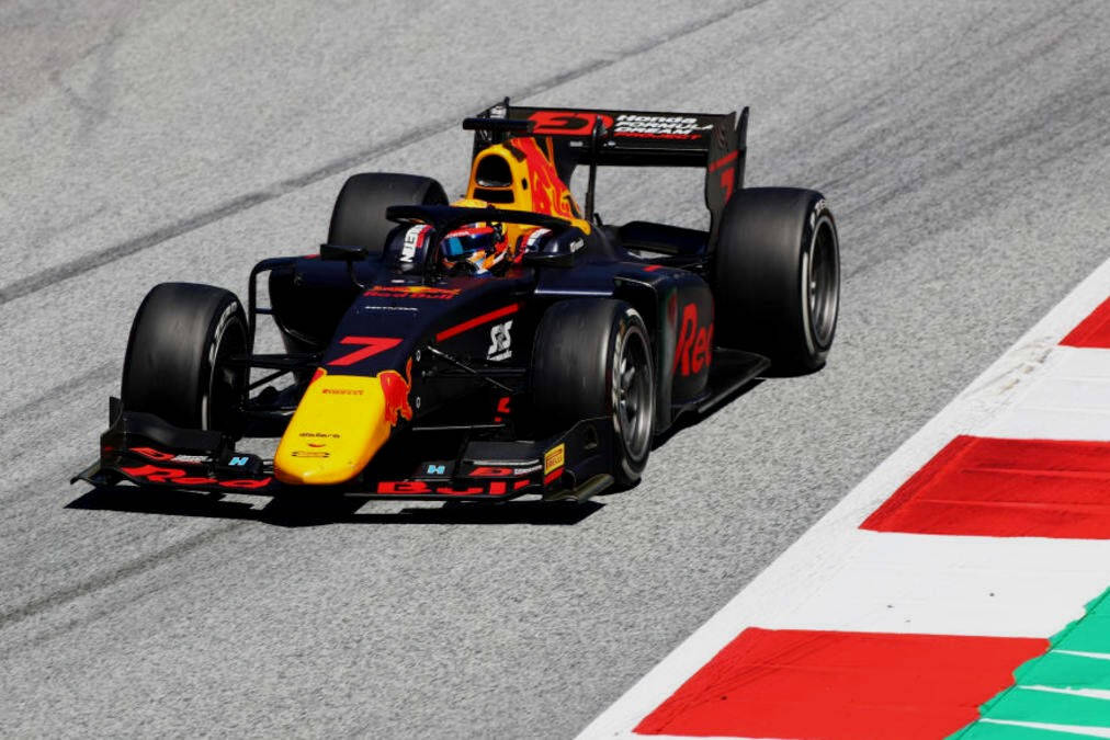 Racing 桌布 壁紙 — 一輛紅牛一級方程式賽車，號碼7，在紅白綠三色路肩的賽道上奔馳，陽光普照。