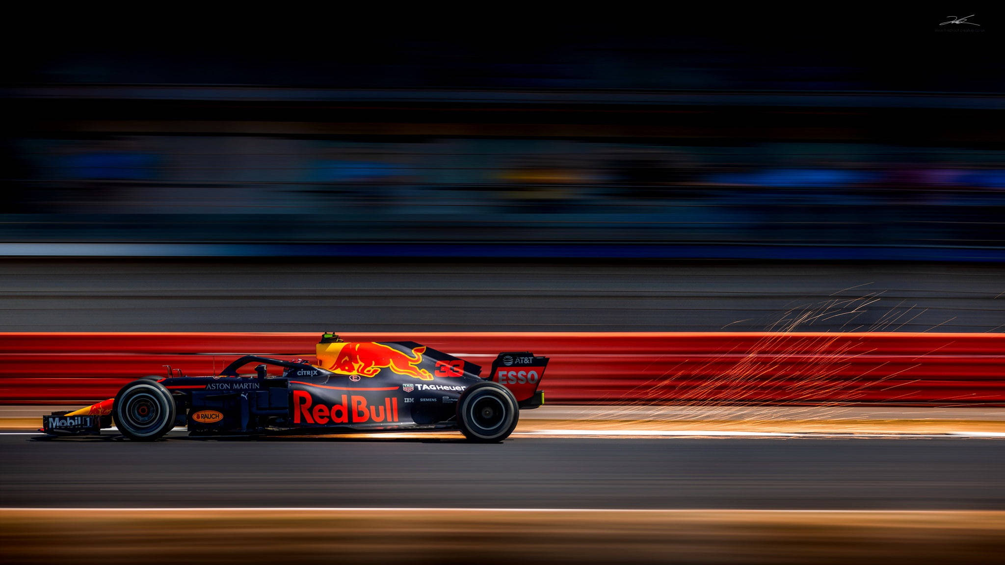 F1 桌布 壁紙 — 一輛紅牛一級方程式賽車在夜間賽道上疾馳而過，帶有動態模糊效果，輪胎迸發出火花。