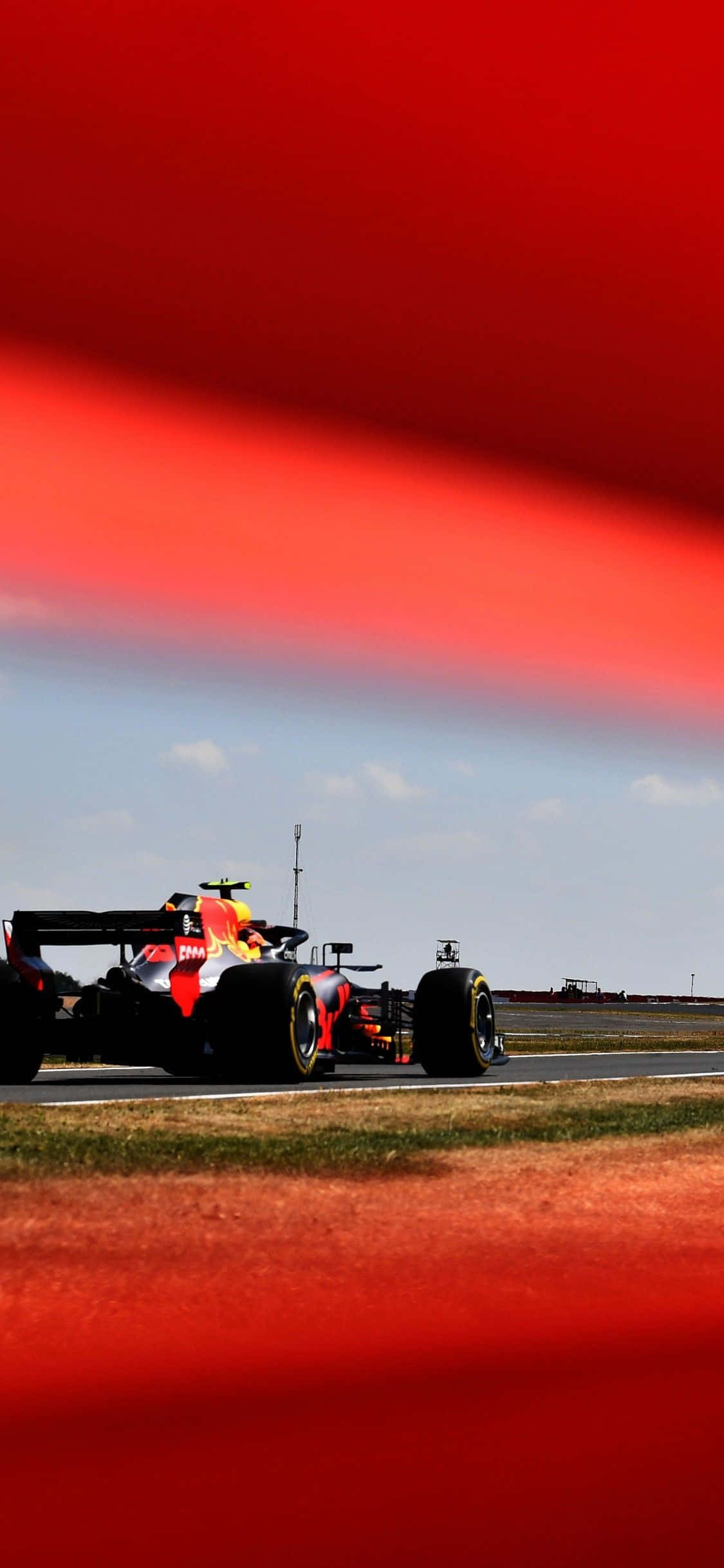 Formula 1 iPhone 桌布 壁紙 — 一輛紅牛一級方程式賽車在賽道上奔馳，賽道以鮮明的紅色抽象線條勾勒，背景是清澈的藍天。