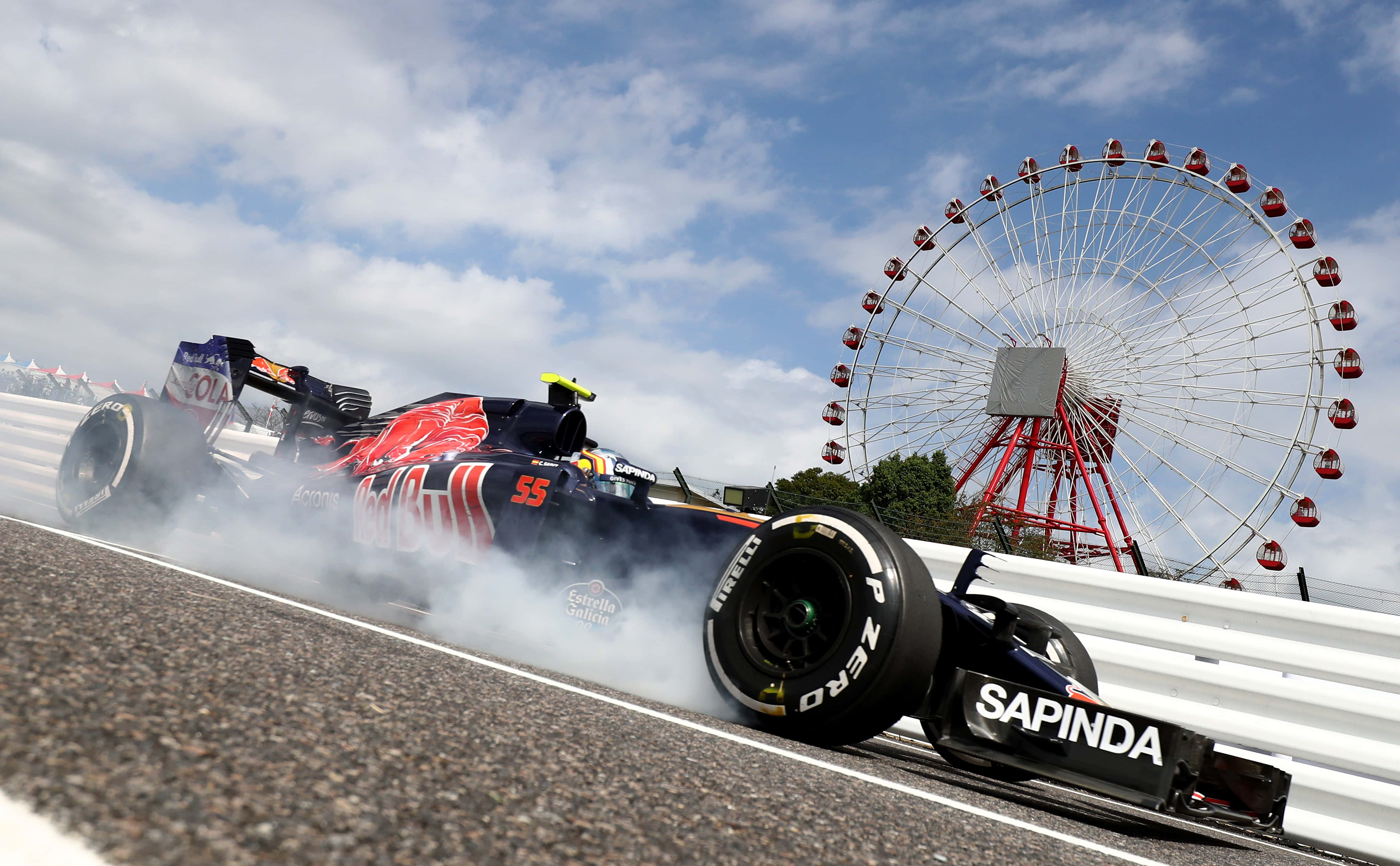 HD F1 2016 桌布 壁紙 — 一輛紅牛一級方程式賽車在賽道上戲劇性地冒煙，背景是一個巨大的摩天輪，天空部分多雲。