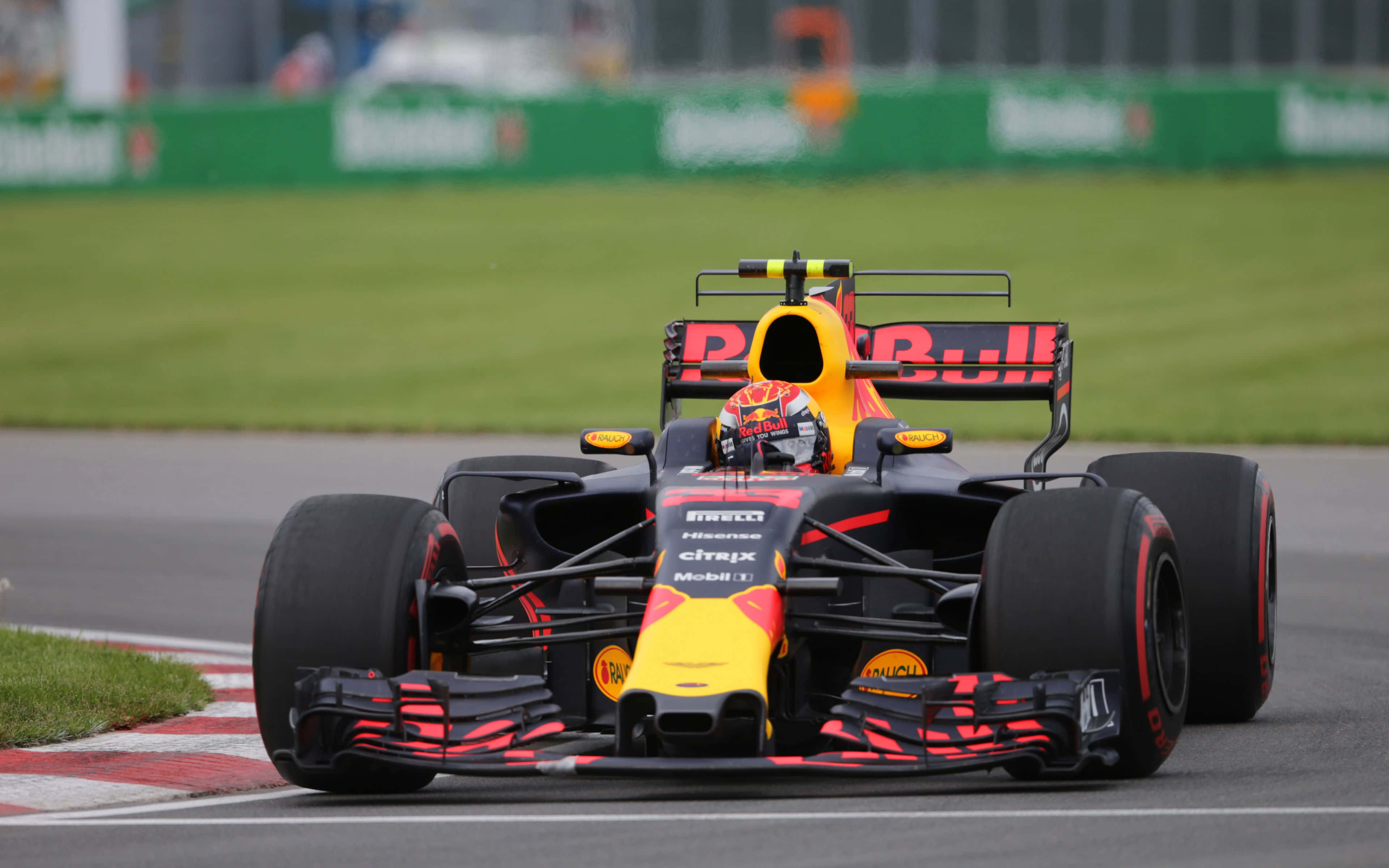 Max Verstappen 桌布 壁紙 — 一輛紅牛一級方程式賽車在賽道上疾馳，駕駛艙內可見戴著頭盔的車手。