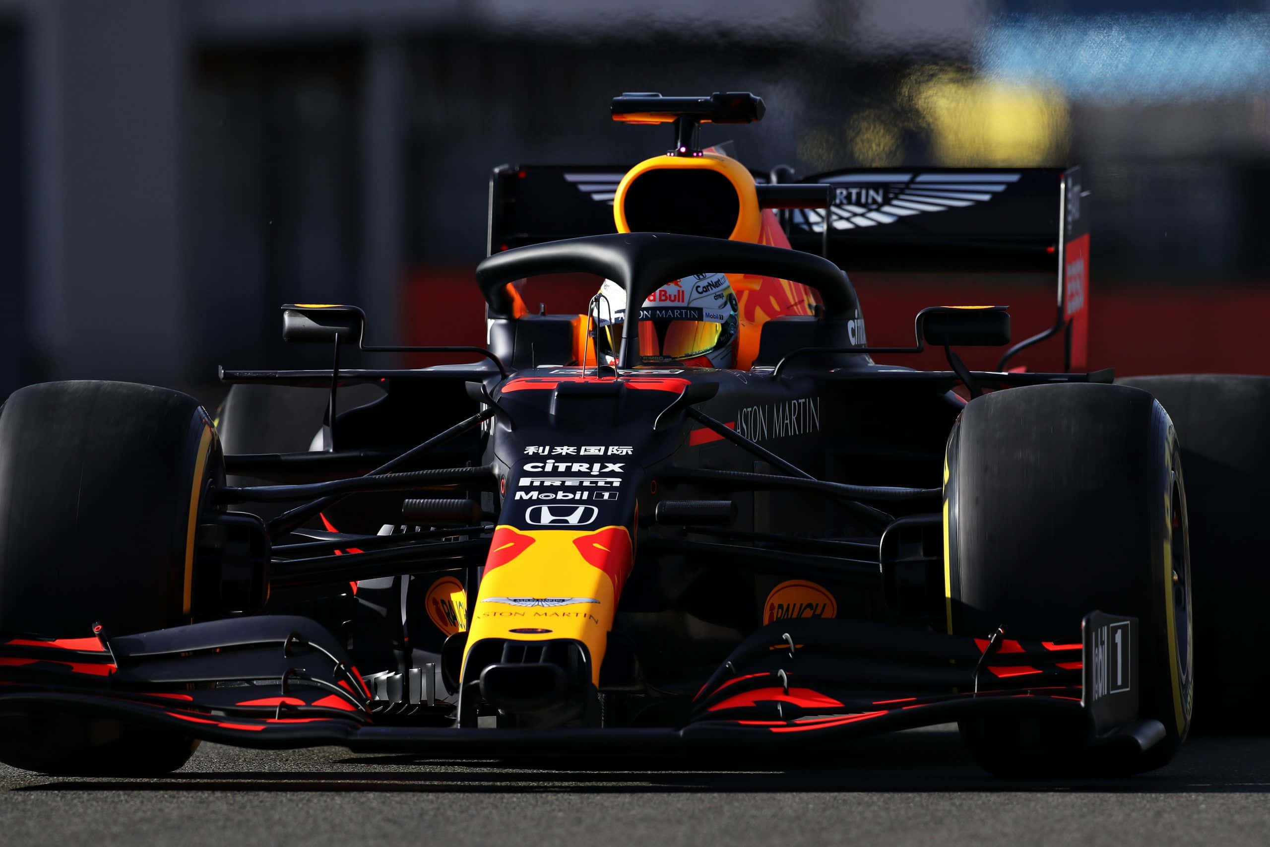 Max Verstappen 桌布 壁紙 — 一輛紅牛車隊一級方程式賽車，帶有鮮豔的橙色和黑色塗裝，在明亮的日光下於賽道上疾馳。