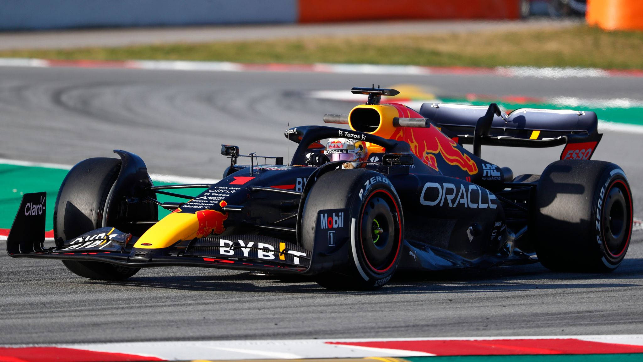 Verstappen 桌布 壁紙 — 一輛紅牛車隊一級方程式賽車在賽道彎道疾馳，帶有鮮明的贊助商標誌和空氣動力學設計。