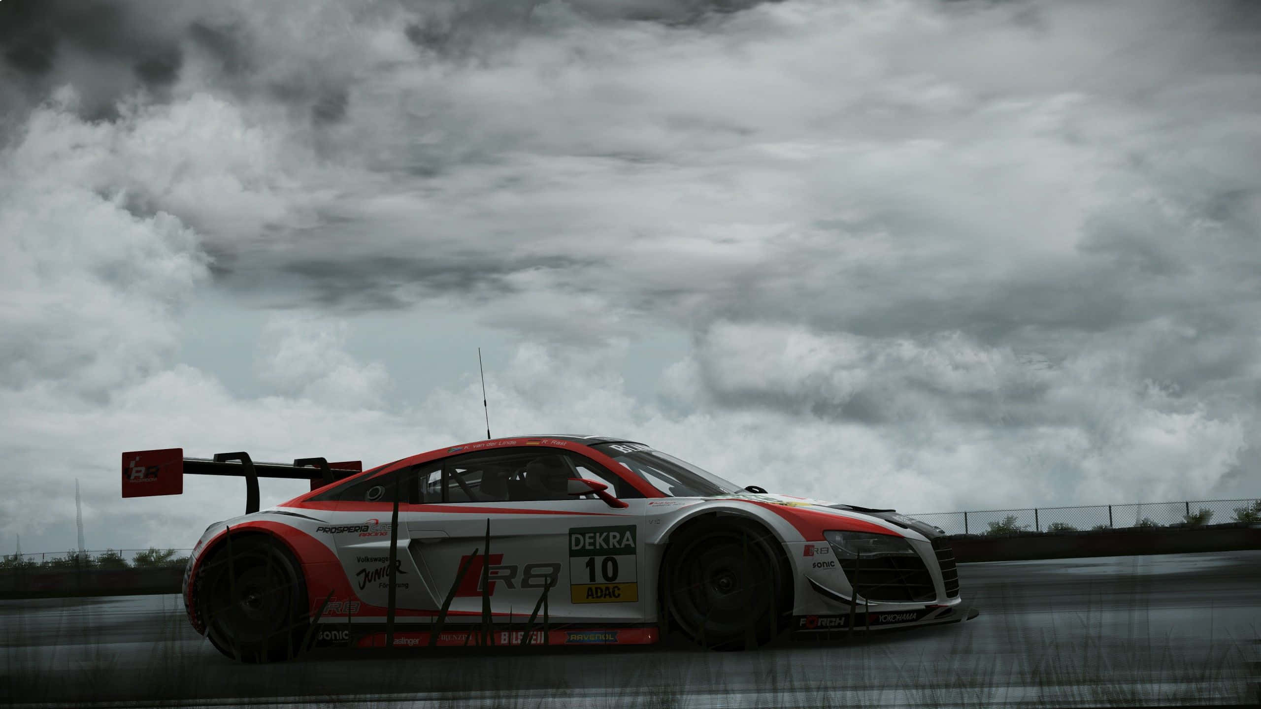 Racing Games 桌布 壁紙 — 一輛紅白相間、編號10的賽車在戲劇性的多雲天空下，在潮濕的賽道上疾馳。