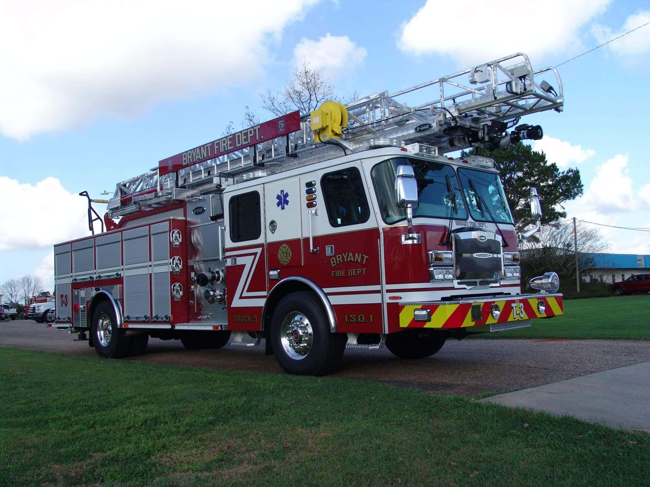 Fire Truck 桌布 壁紙 — 一輛紅白相間的 Bryant 消防局雲梯車停在草地上，天空局部多雲。