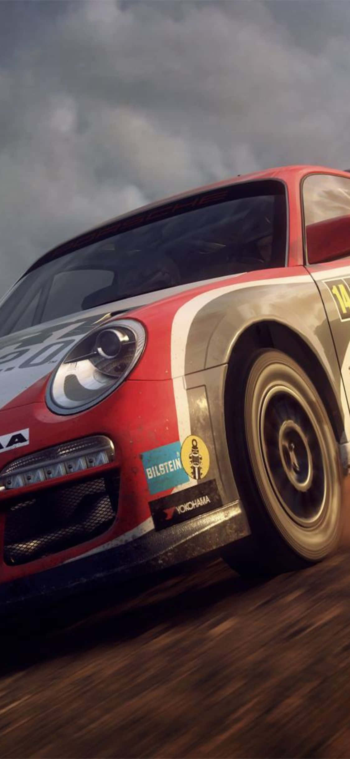 iPhone X Dirt Rally 桌布 壁紙 — 一輛紅白相間的拉力賽車在暴風雨的天空下疾馳穿過泥濘的森林賽道。