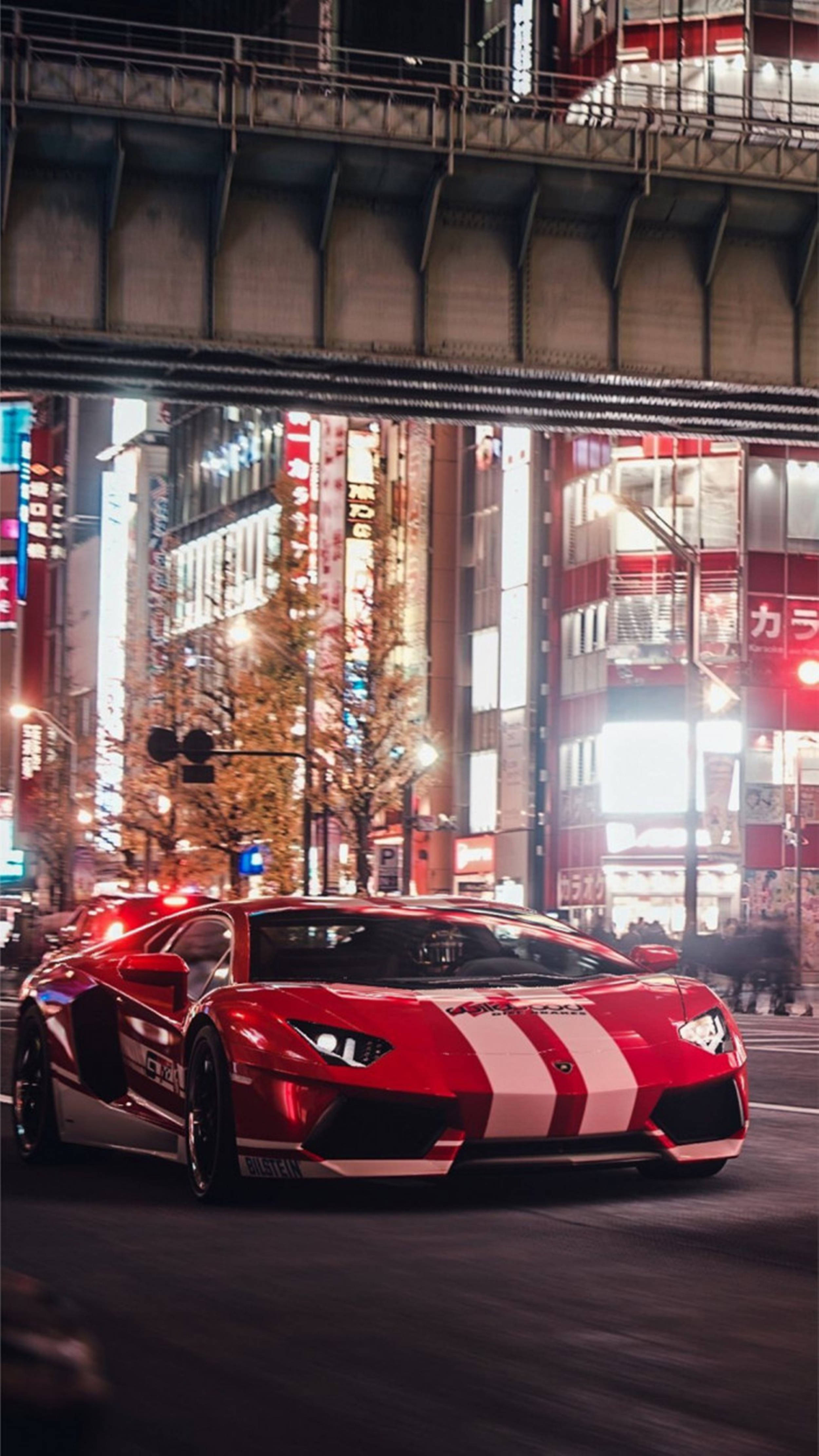 street photography 桌布 壁紙 — 一輛紅白色的藍寶堅尼Aventador在夜晚的天橋下，疾馳穿過霓虹燈閃爍的東京街道。