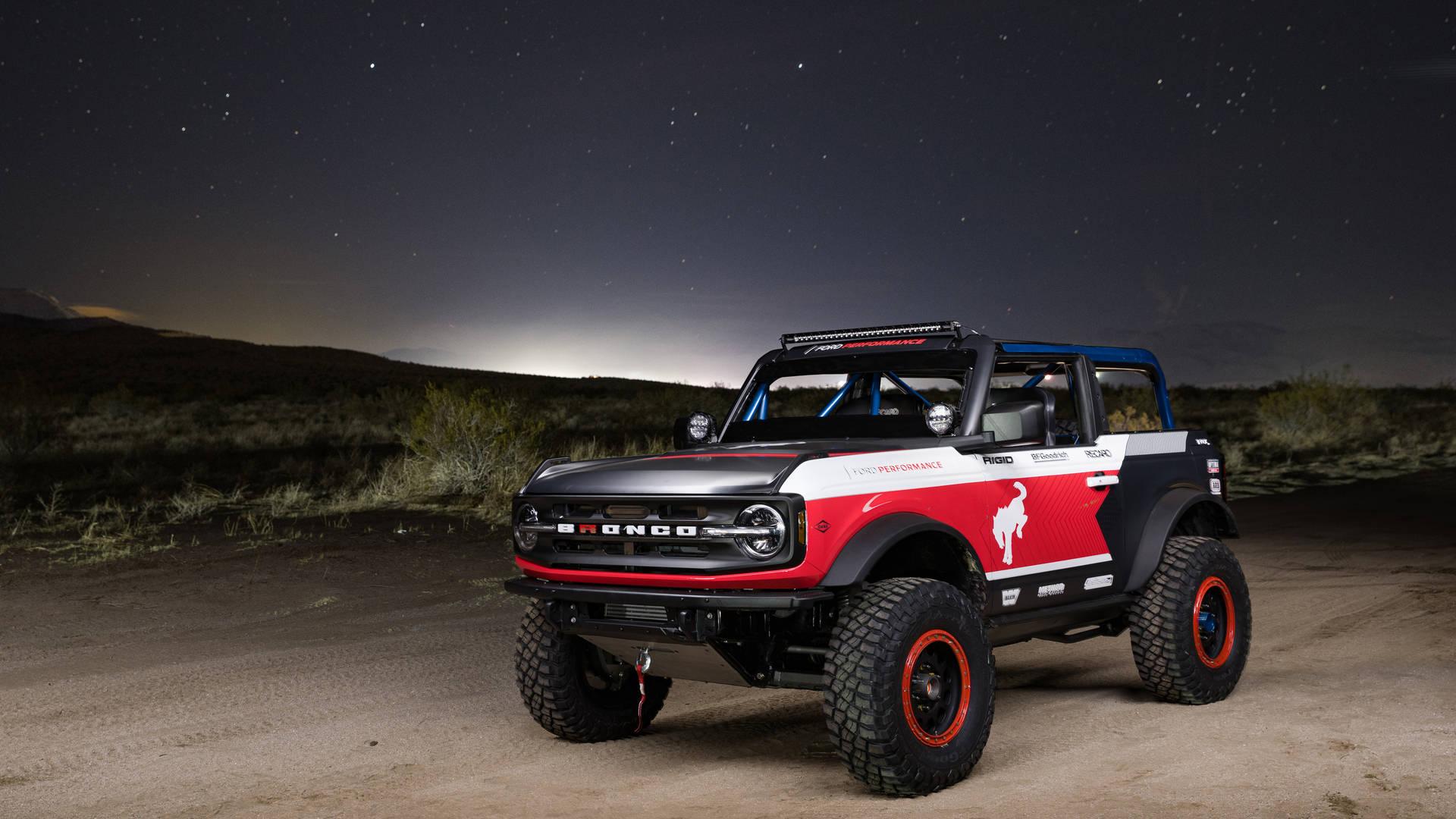Ford Bronco 桌布 壁紙 — 一輛紅白黑色的福特 Bronco 越野車在沙漠景觀中，站在星空下。