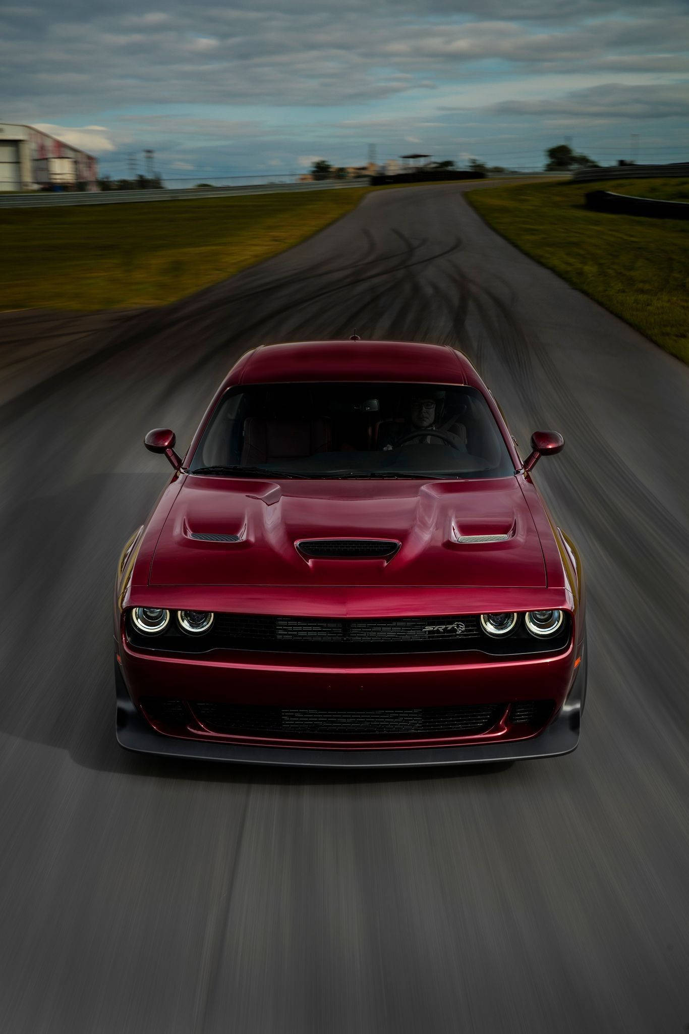 Challenger 桌布 壁紙 — 一輛紅色 Dodge Challenger SRT Hellcat 在賽道上高速行駛，在陰天留下輪胎痕跡。
