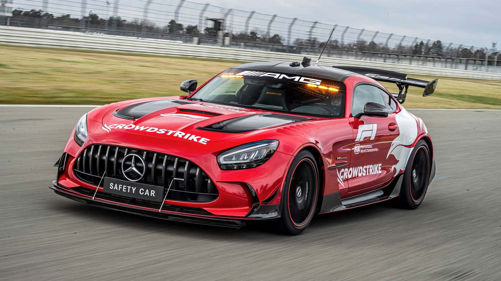 汽車 桌布 壁紙 — 一輛紅色 Mercedes-AMG GT 安全車在賽道上高速行駛，帶有動態模糊效果和贊助商貼紙。