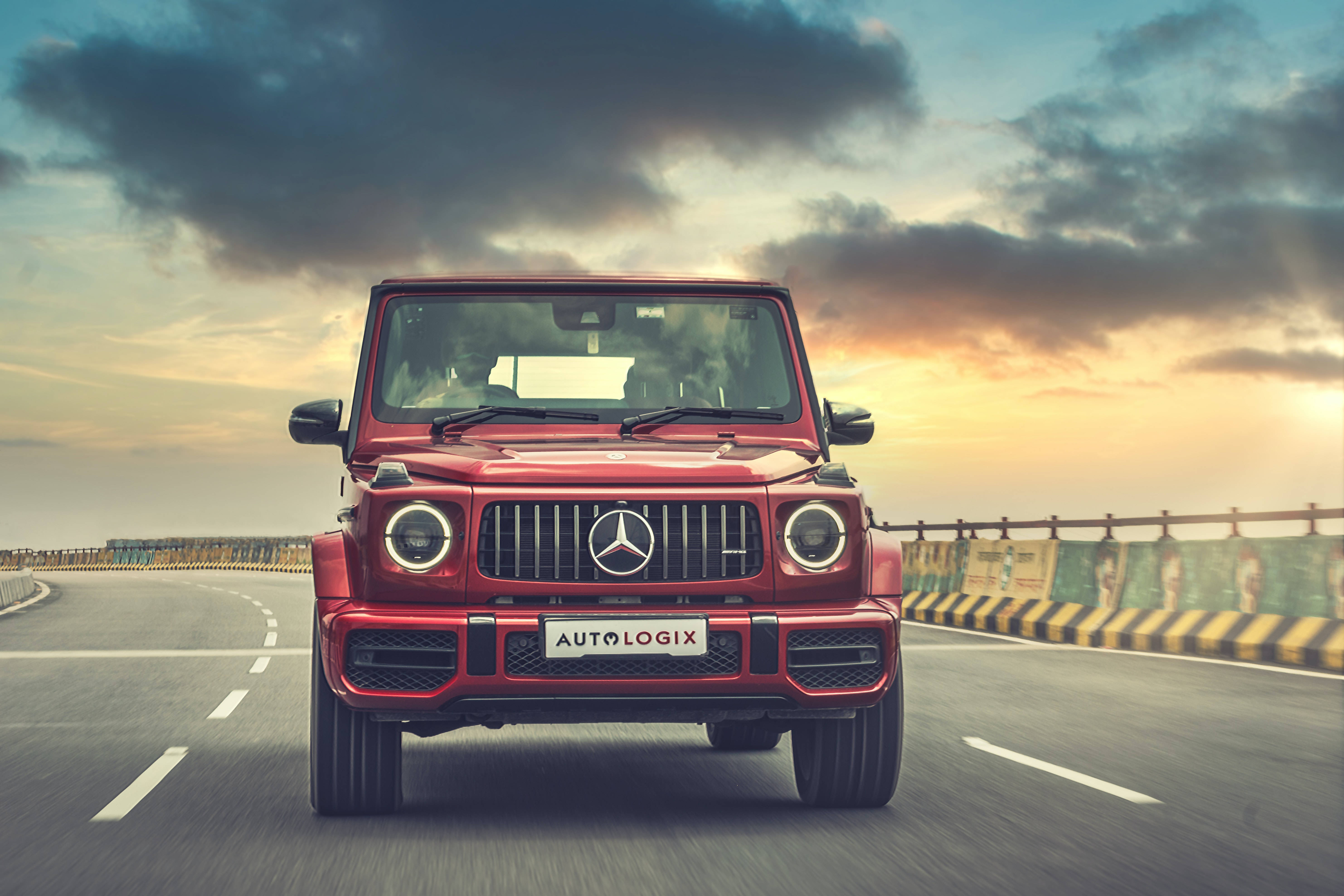 Cool Car 桌布 壁紙 — 一輛紅色 Mercedes G-Wagen 在高速公路上駛向鏡頭，背景是帶有烏雲的戲劇性日落天空。