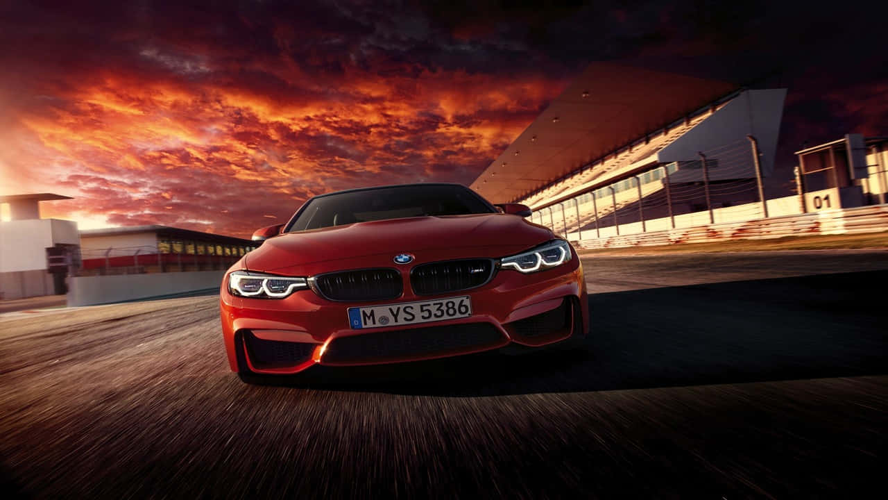 720p Bmw 桌布 壁紙 — 一輛紅色BMW M4在火紅橙紫相間的夕陽天空下於賽道上飛馳。