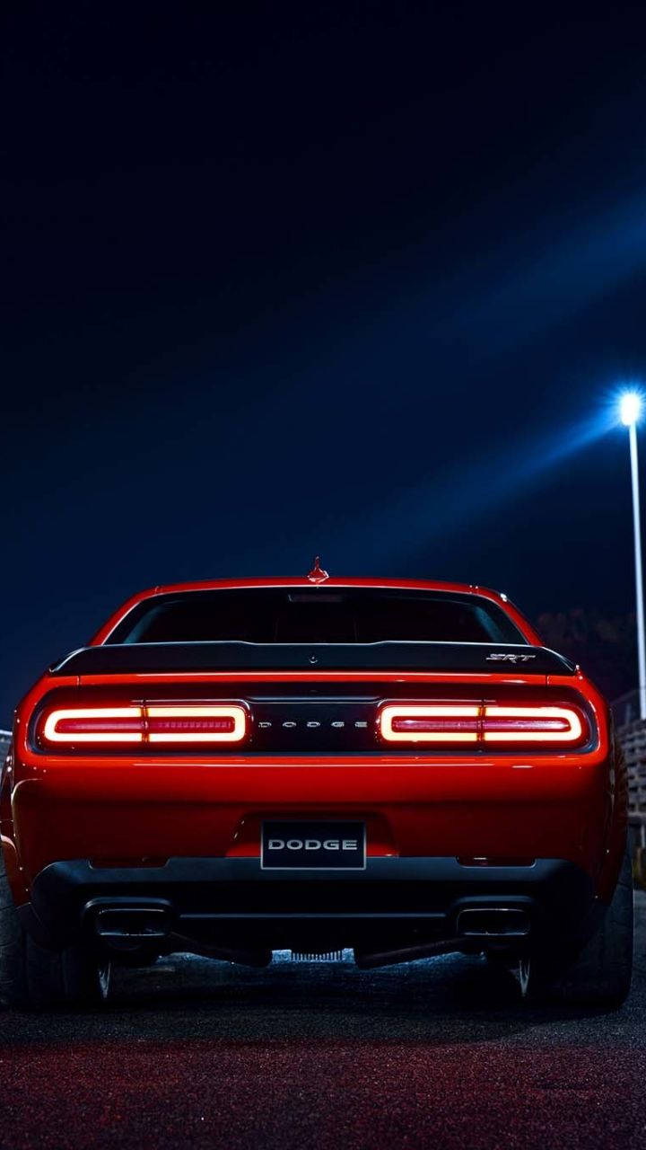 Challenger 桌布 壁紙 — 一輛紅色Dodge Challenger SRT在夜間單一明亮街燈下發光的後視圖。