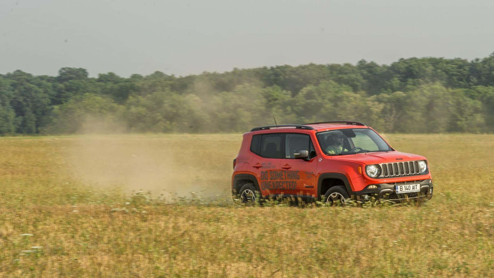 Jeep Renegade 桌布 壁紙 — 一輛紅色Jeep Renegade駛過乾燥的草地，揚起灰塵，背景有樹木。