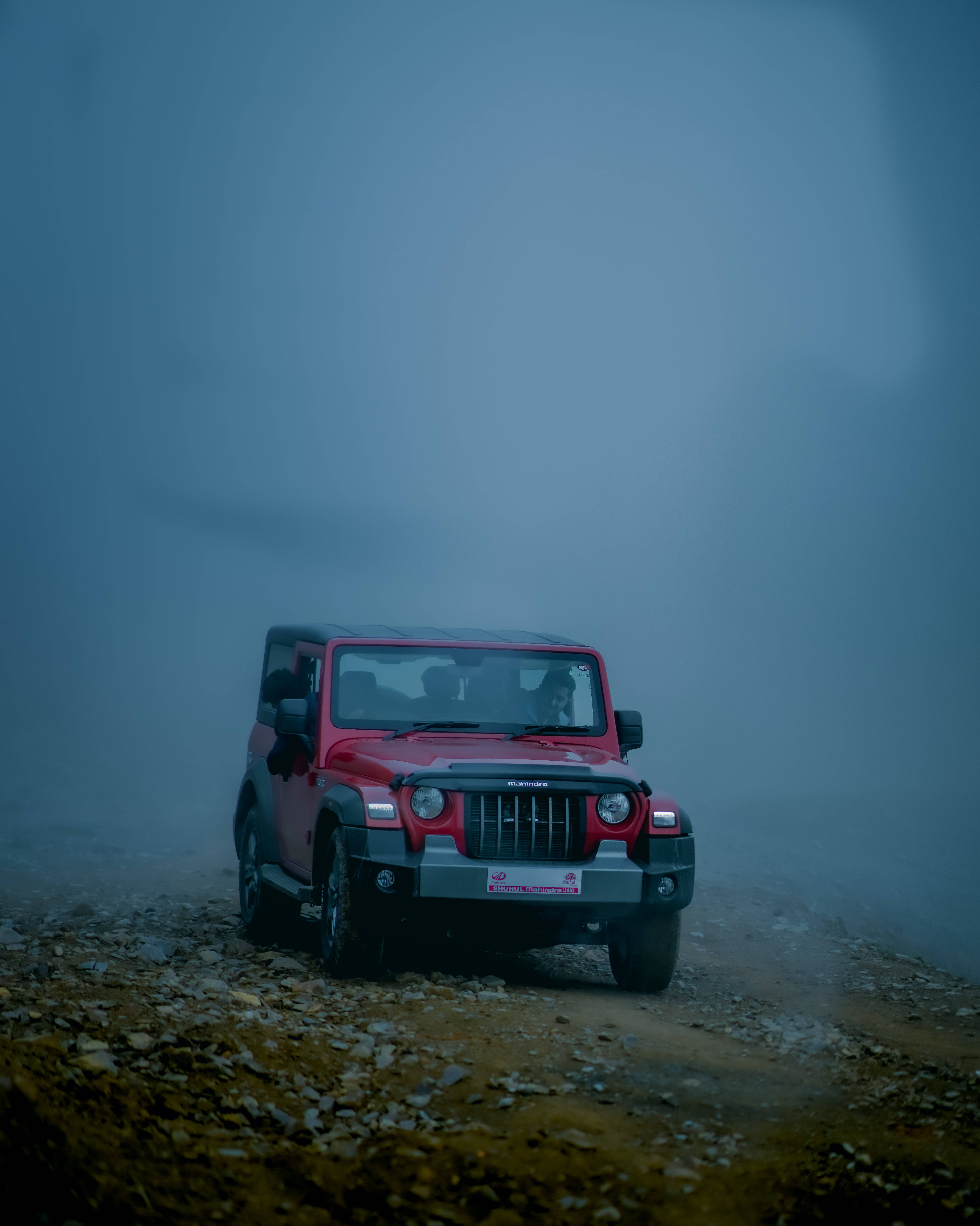 人像動態 桌布 壁紙 — 一輛紅色Jeep Wrangler在朦朧藍天下沿著霧氣瀰漫的山路行駛。