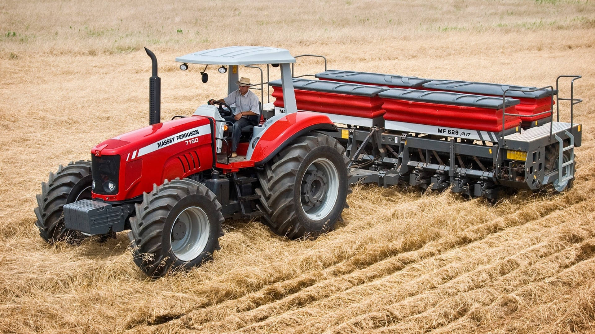 Farmer 桌布 壁紙 — 一輛紅色Massey Ferguson拖拉機與農夫駛過金色收割田，拖著紅色播種機。