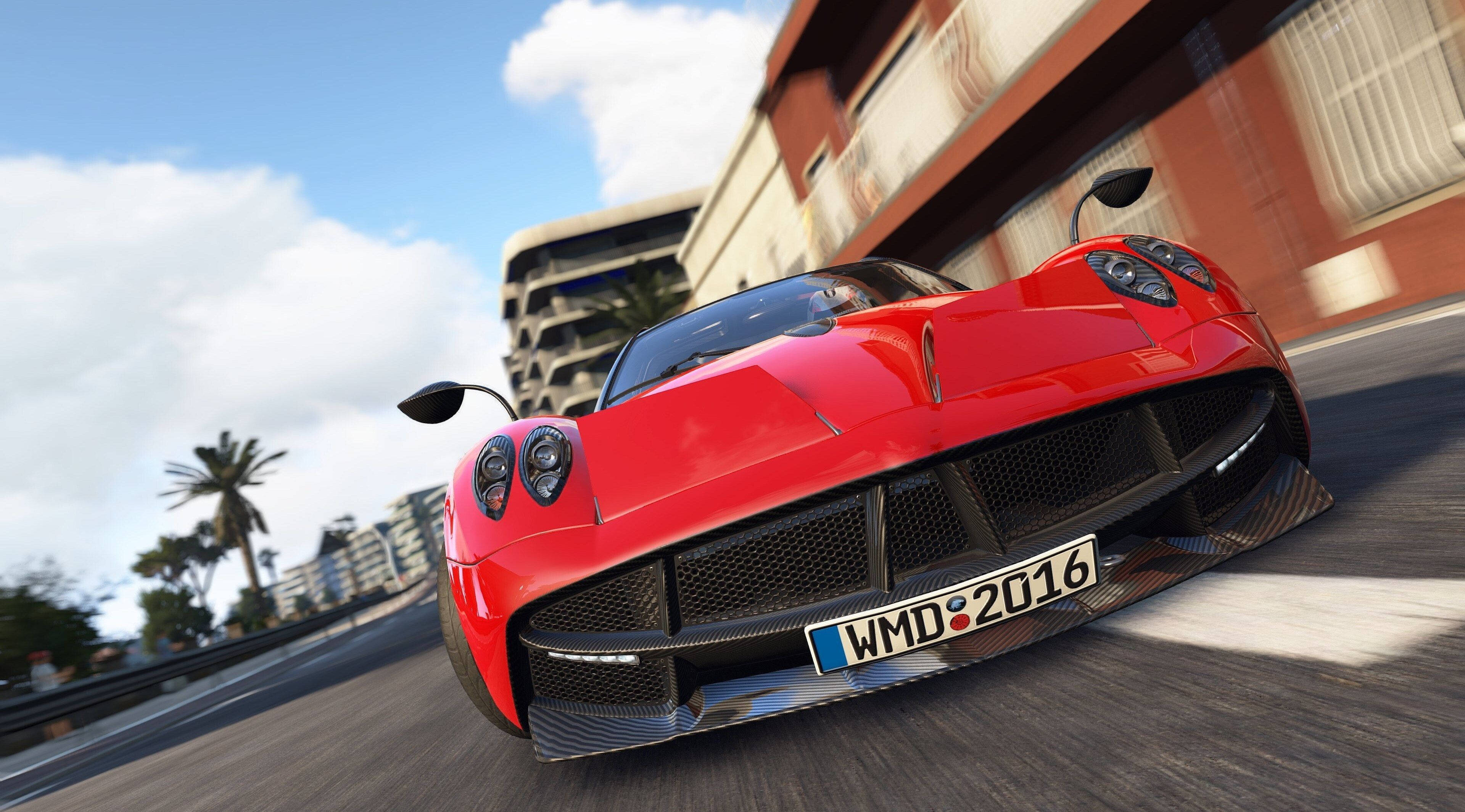 cars 桌布 壁紙 — 一輛紅色Pagani Huayra在晴朗藍天下，沿著種有棕櫚樹和現代建築的海岸賽道疾馳。