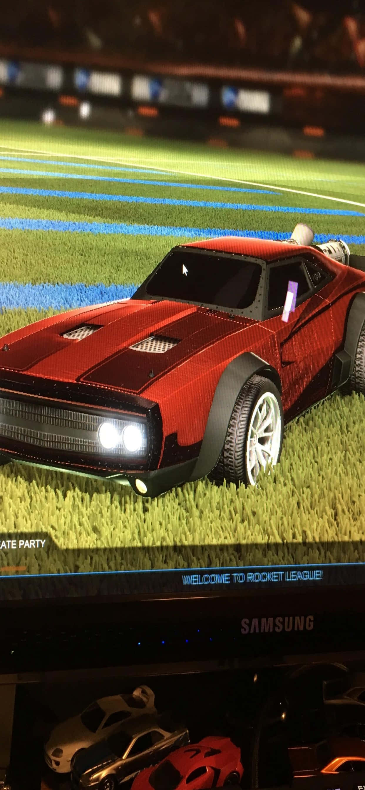 iPhone Xs Max Rocket League 桌布 壁紙 — 一輛紅色Rocket League賽車，帶有發光車頭燈，停在體育場燈光下的綠色場地上。