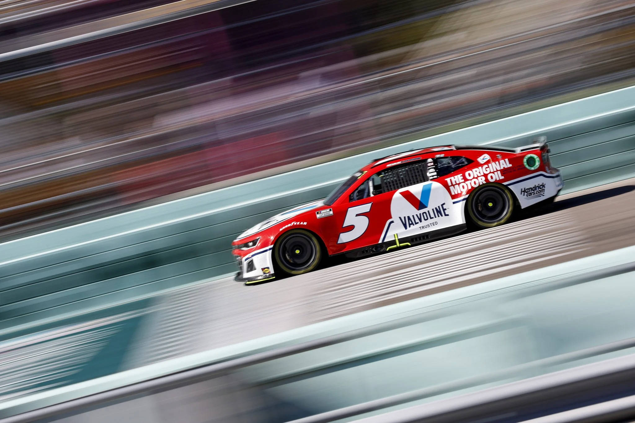 Kyle Larson 桌布 壁紙 — 一輛紅色Valvoline賽車在賽道上疾馳，背景因動態模糊而呈現條紋效果。