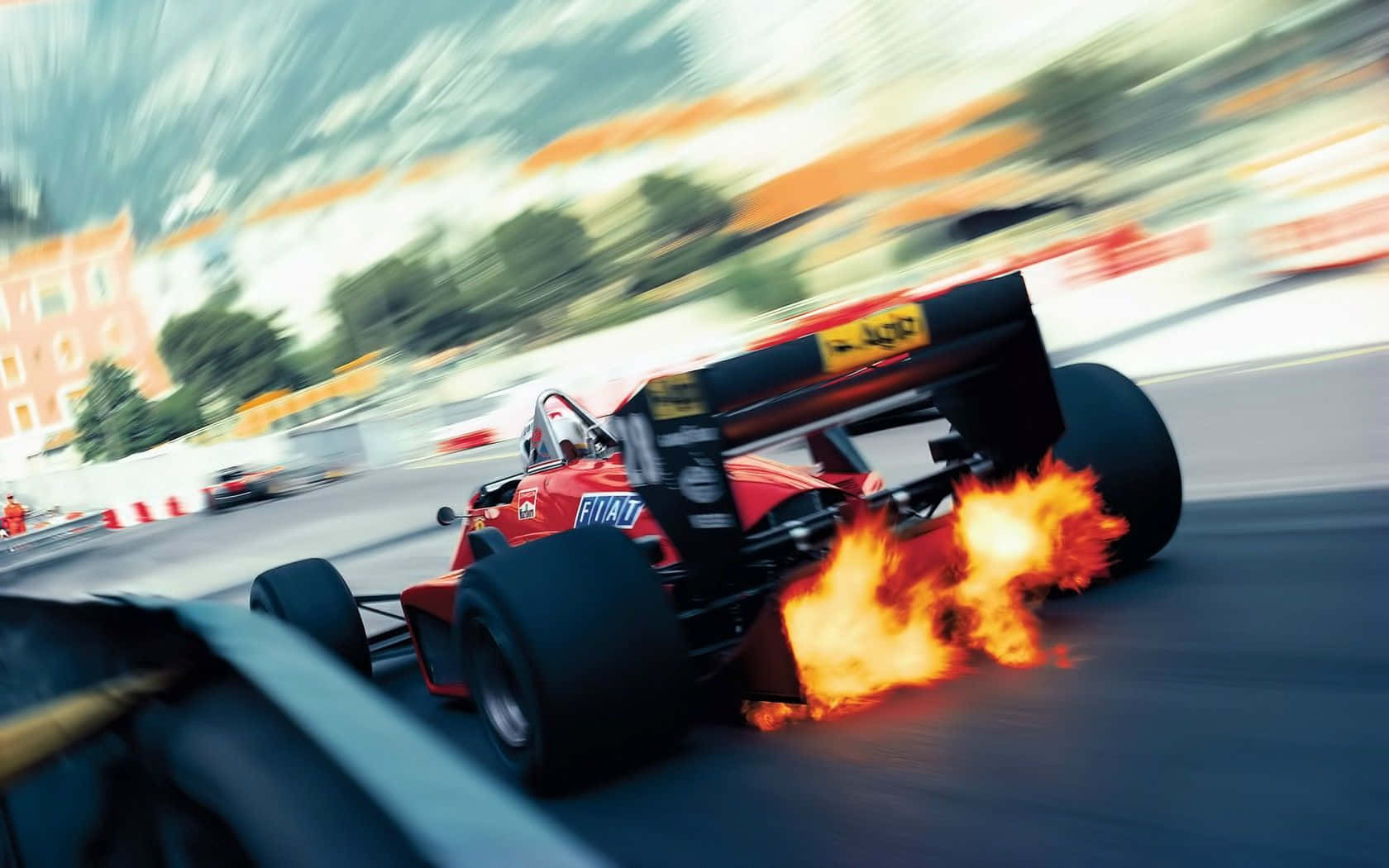 Race Track 桌布 壁紙 — 一輛紅色一級方程式賽車在高速行駛時起火燃燒，周圍環境模糊。